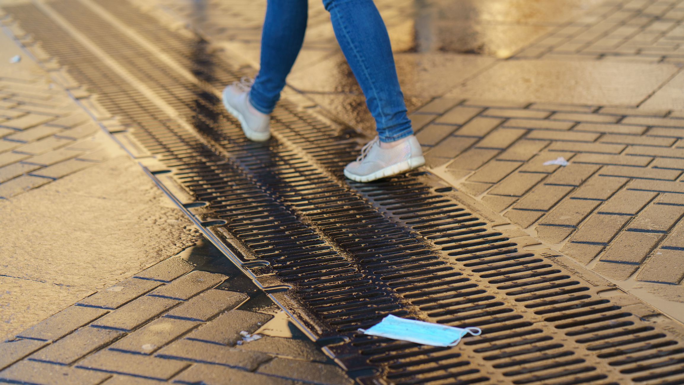 a person walking along a city street past a discarded mask