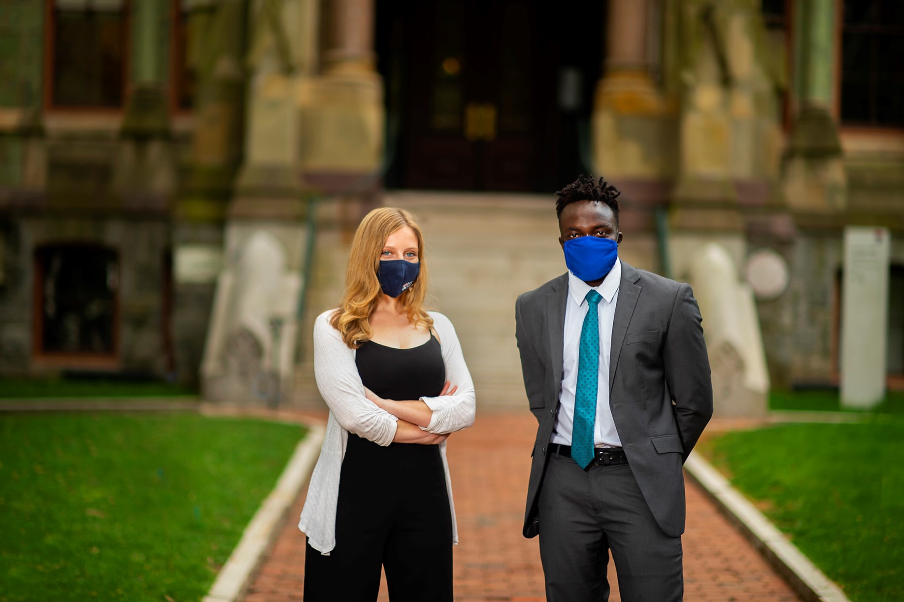 Leah Voytovich and Martin Leet in front of college hall while wearing masks