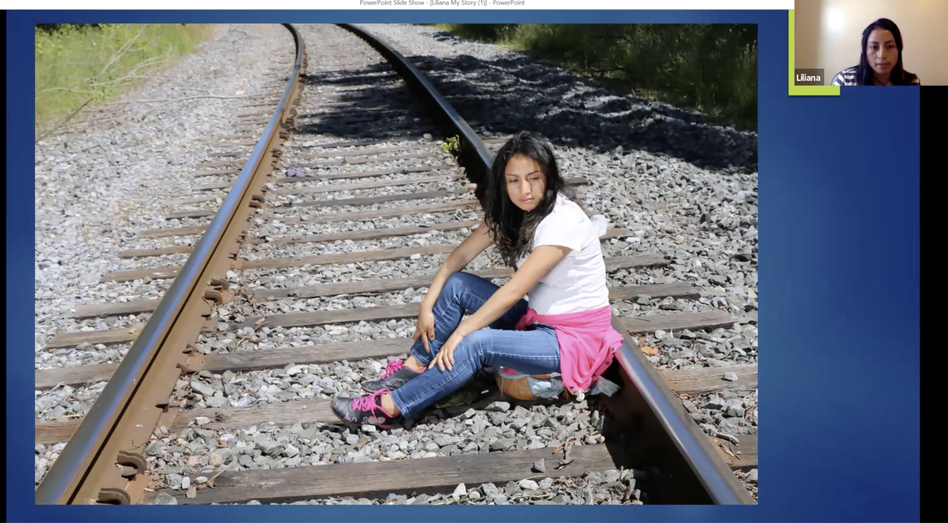 Young woman sits on railroad tracks