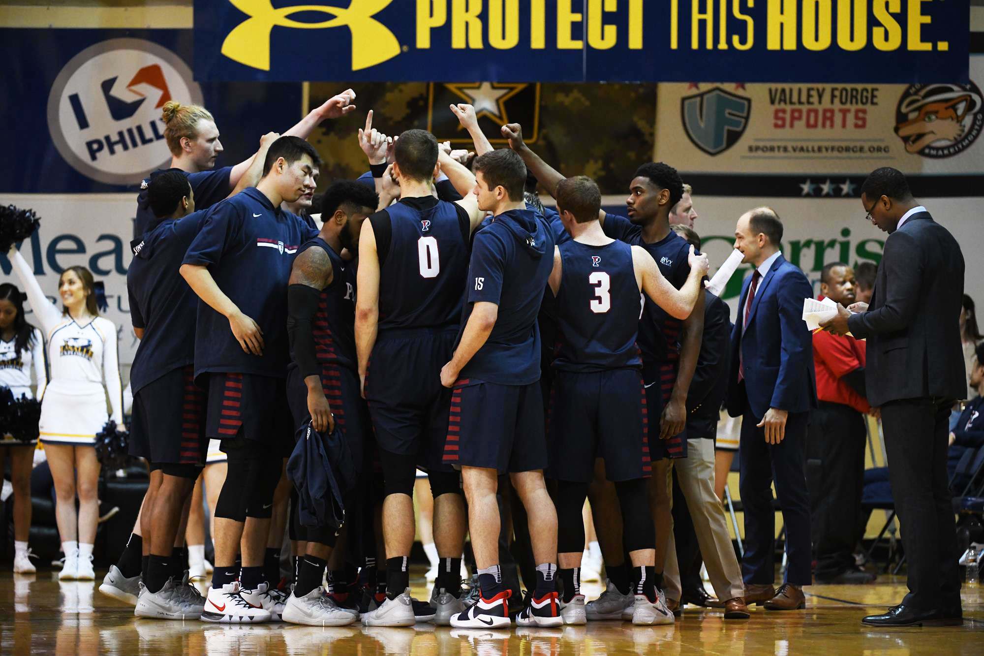 Members of the men's basketball team put their hands in circle during a huddle.