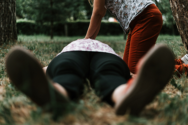Person performing chest compressions on a person laying in the grass.