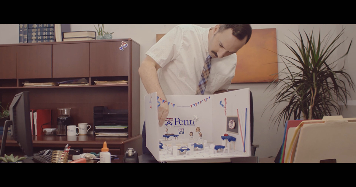 Film still from Eat Wheaties! showing Tony Hale building a Penn-themed diorama on a desktop.