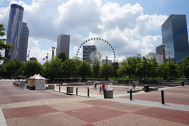 Brick plaza with splashground, ferris wheel, and skyscrapers in the background