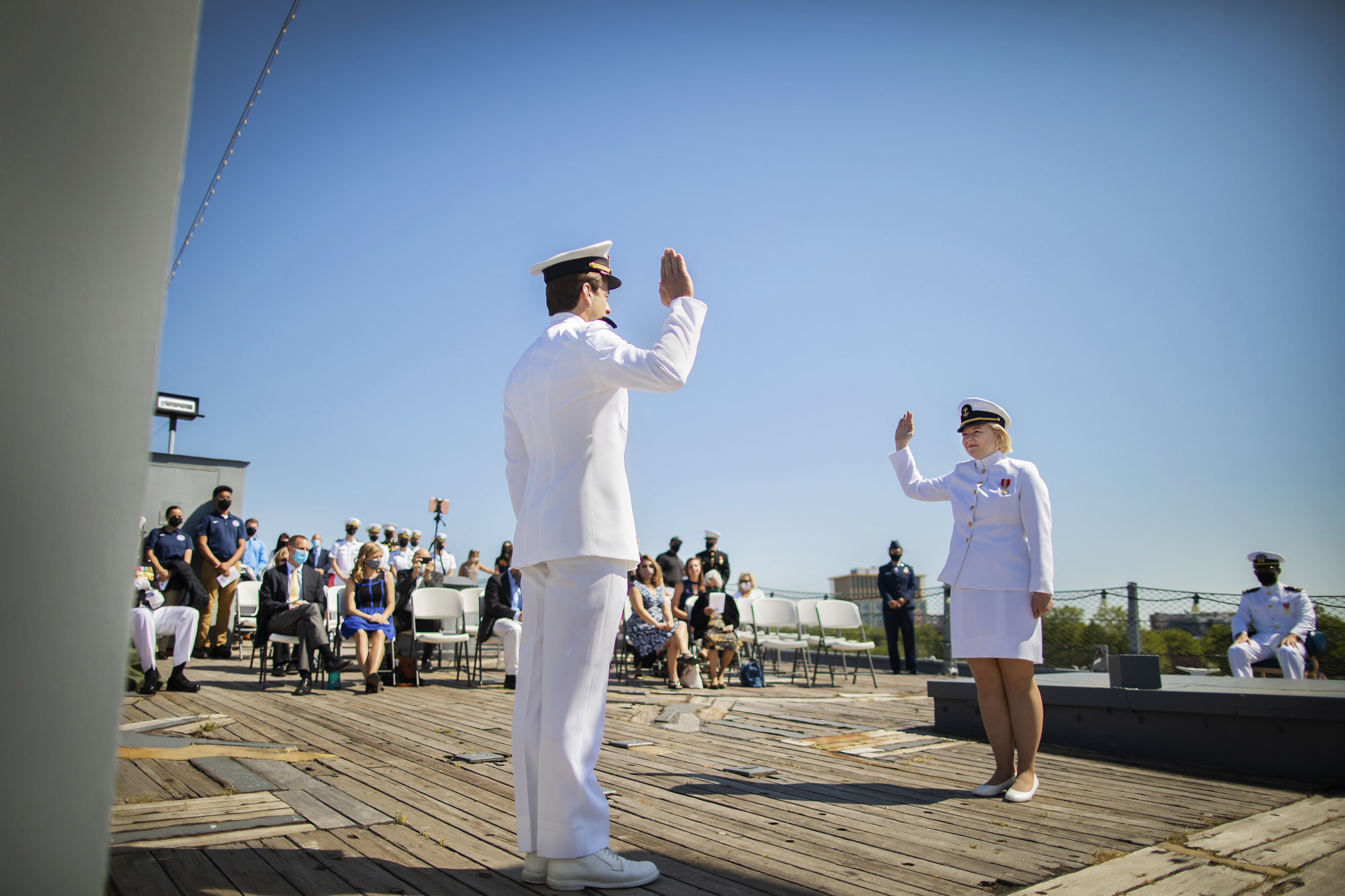 Two people in uniform raising their right hands standing on deck on the USS New Jersey.