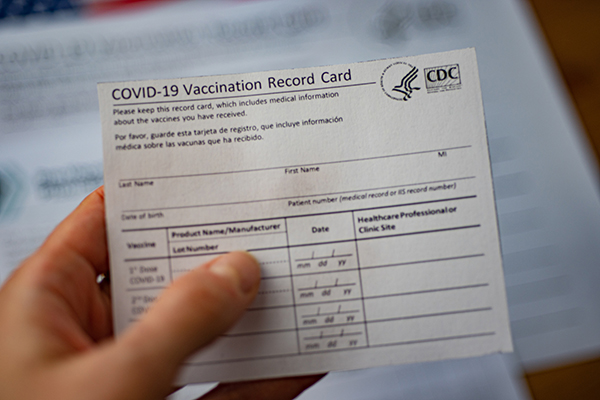 Hand holding a blank COVID-19 vaccination card.