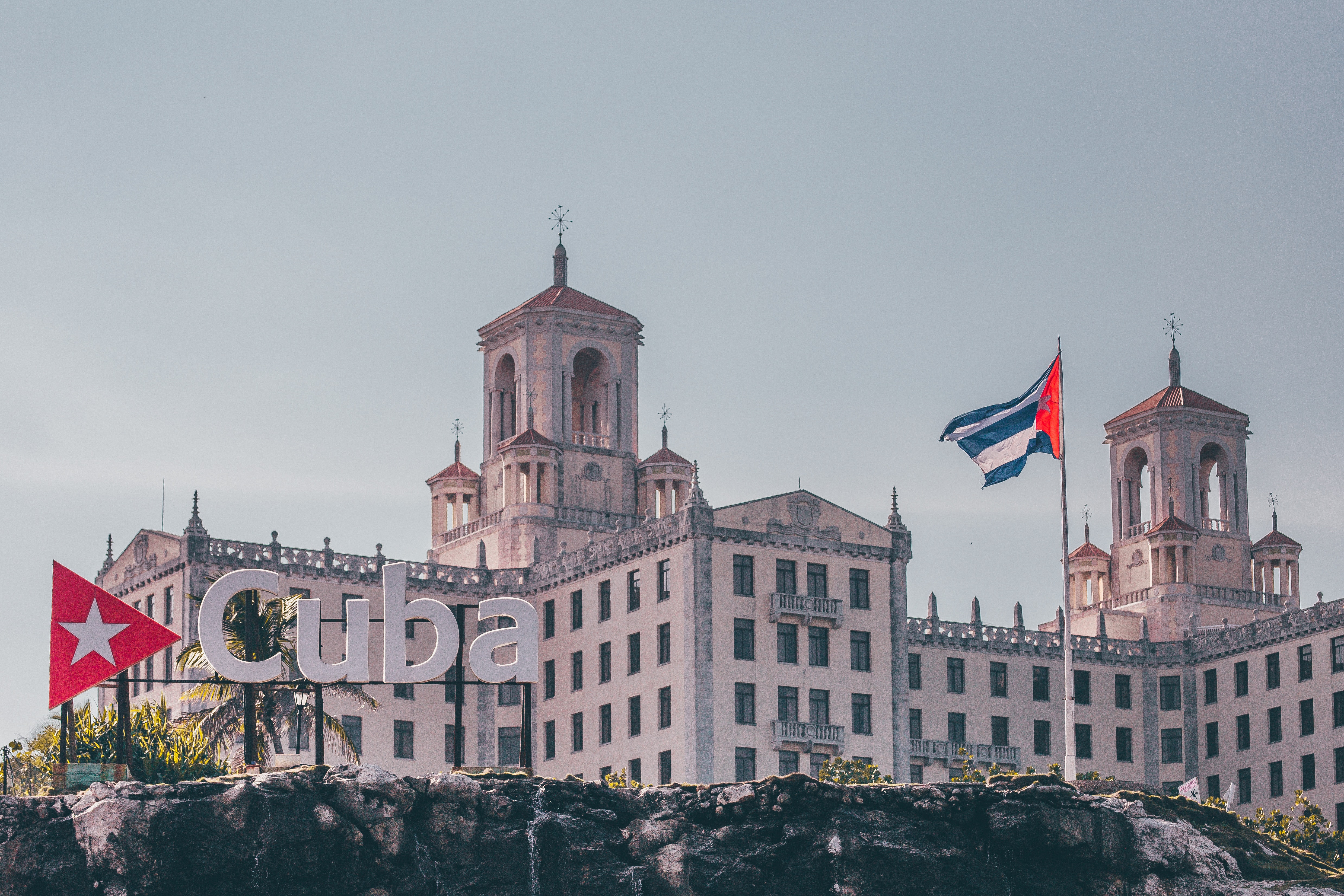 A larger building flies the Cuban flag. A sign in front says "Cuba" 