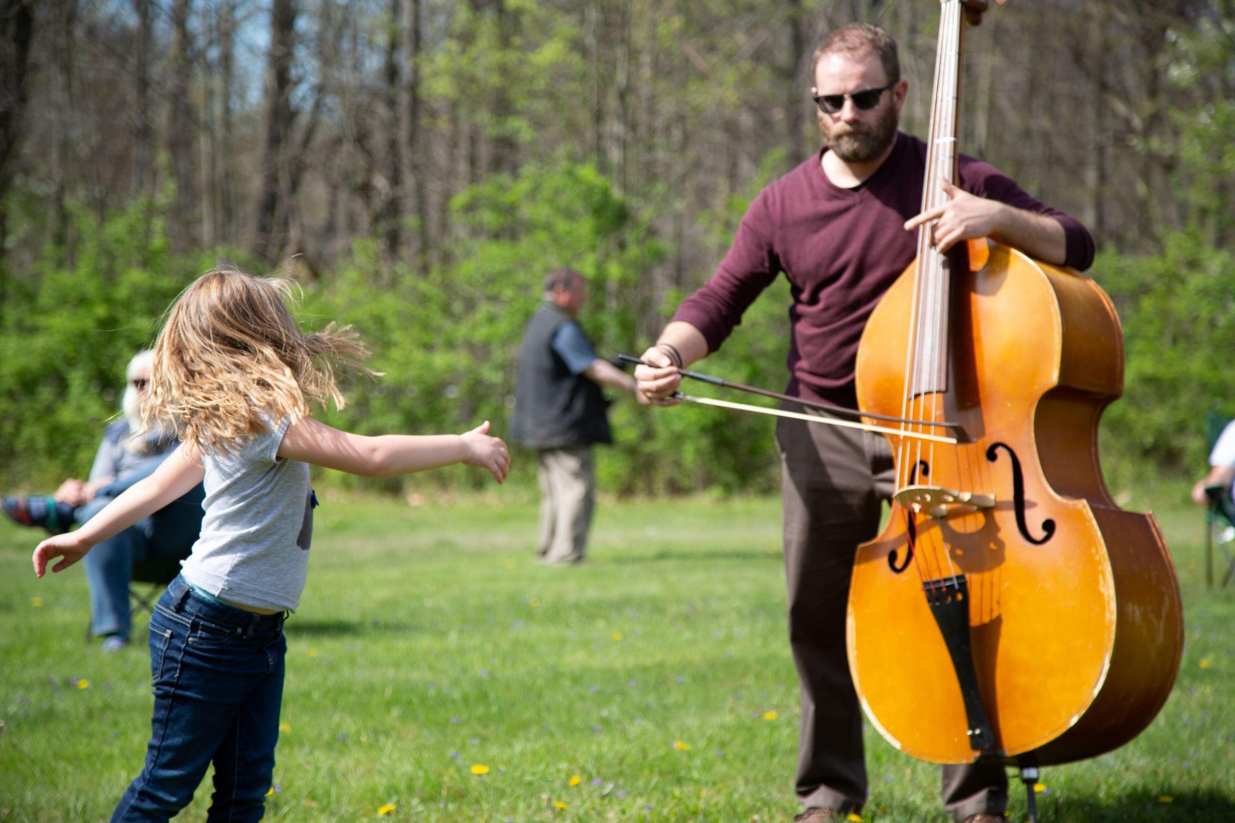 Man with cello outside with child dancing