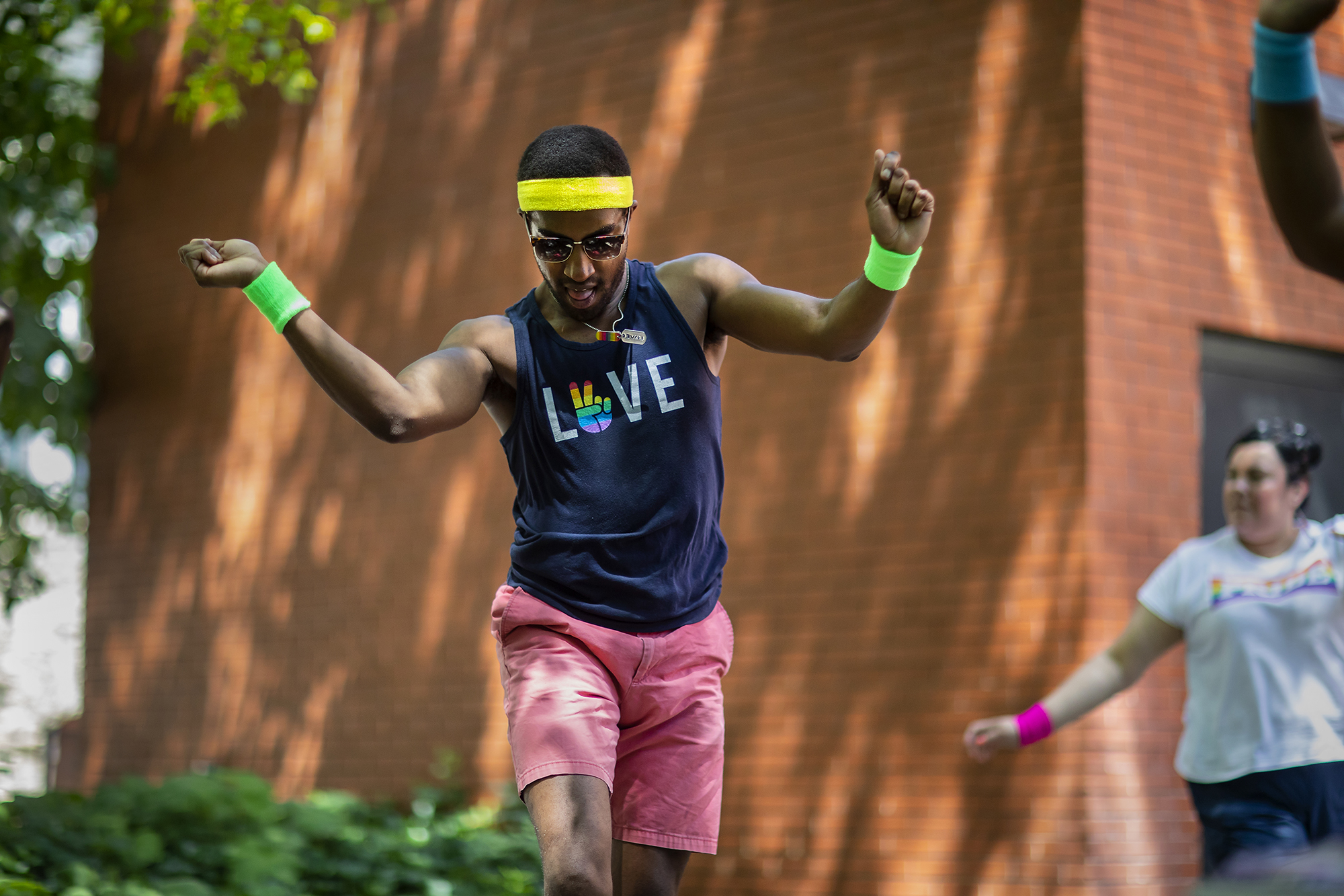 A person wearing a sweatband and wristbands dances outside in a Penn courtyard.