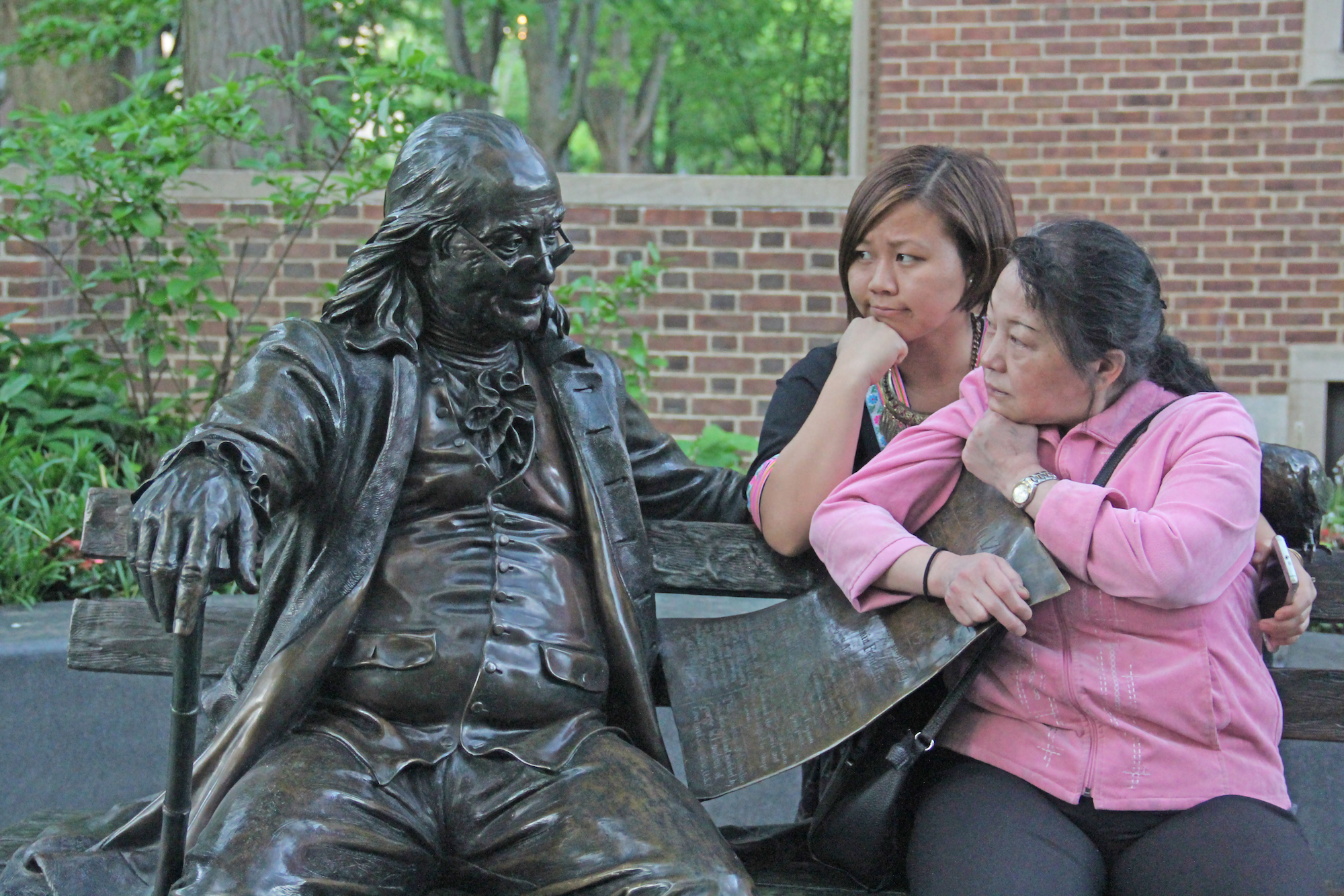 Two women pose with Ben Franklin statue