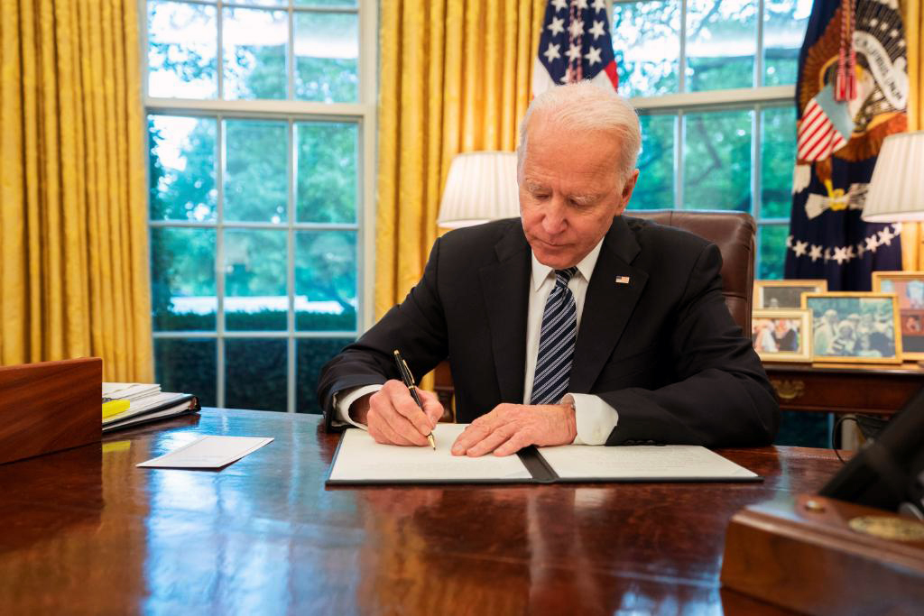 President Biden signing an executive order in the Oval Office.