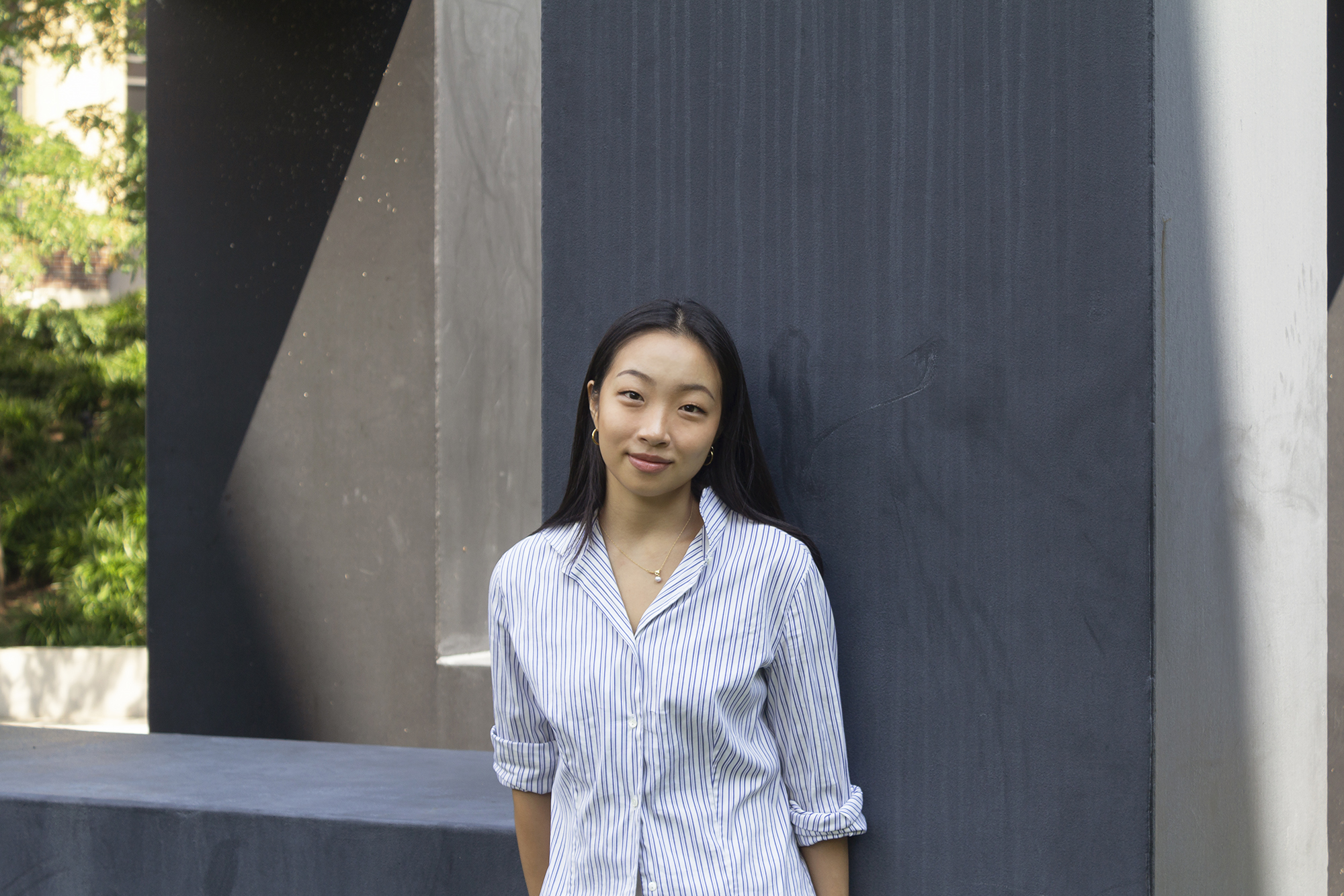 student standing outside with large sculpture behind 