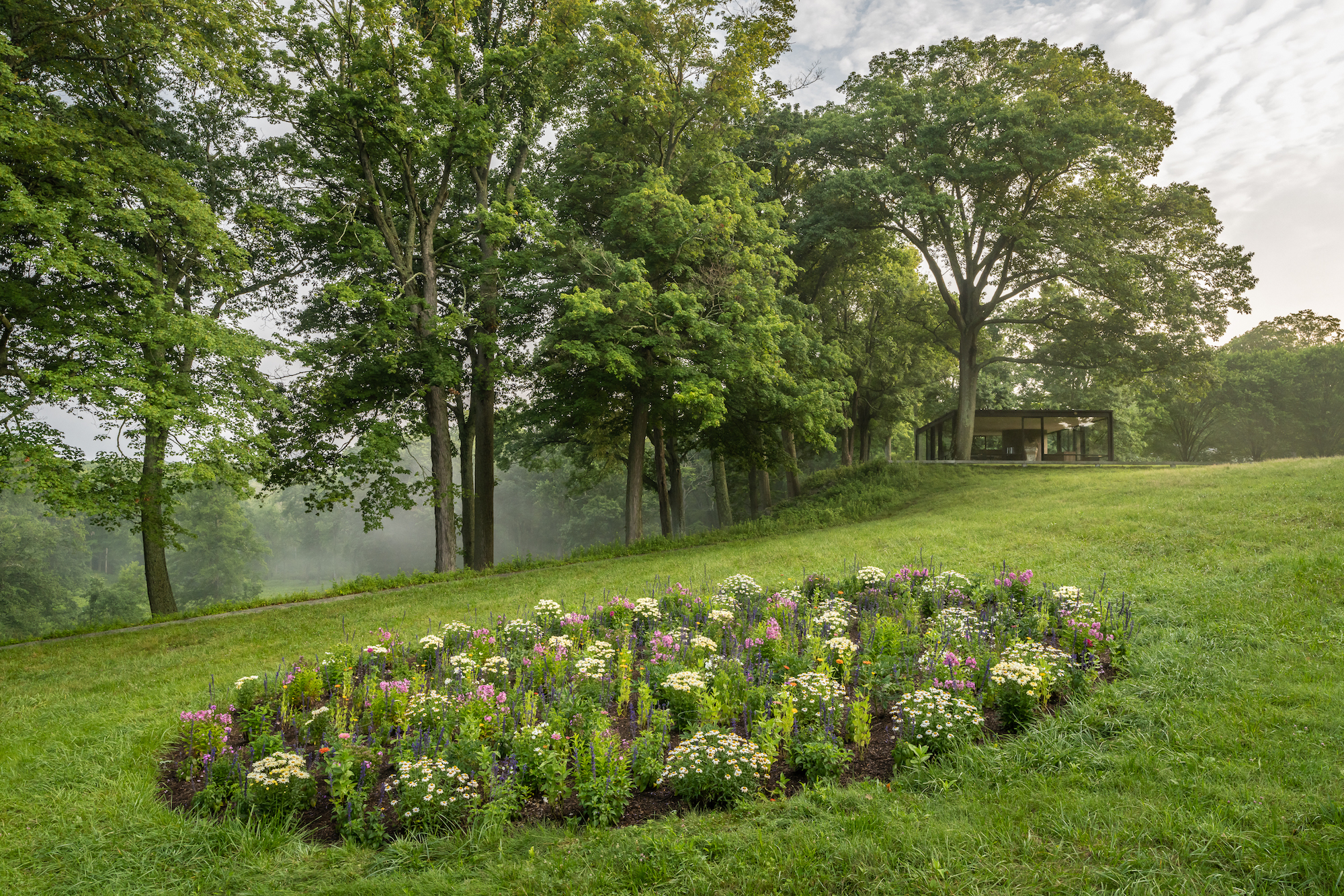 a circular garden of flowers surrounded by lush grass and trees 