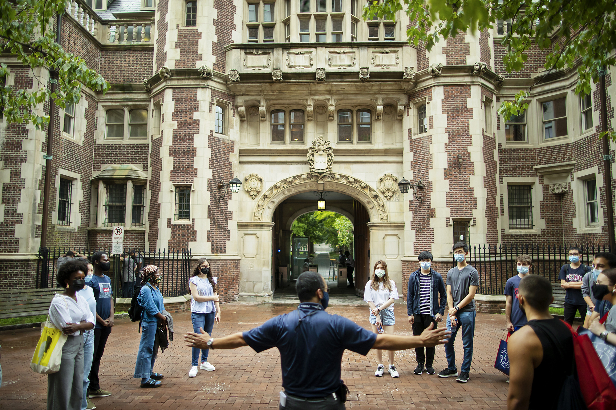 Several students standing outside in front of a historic brick dorm building