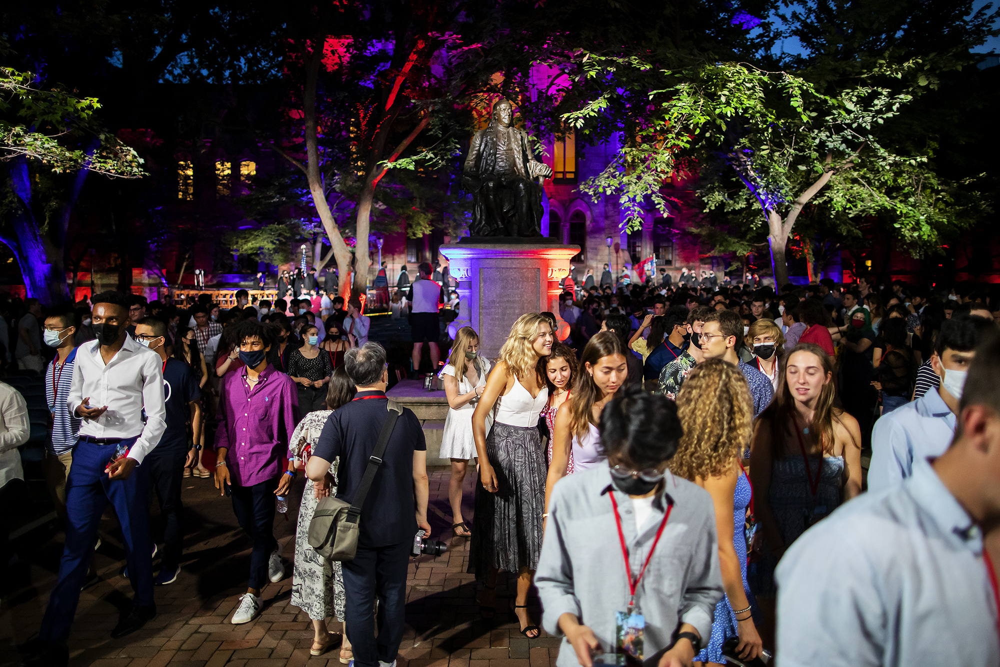 Students standing around the Ben Franklin statue under the lights of College Hall.