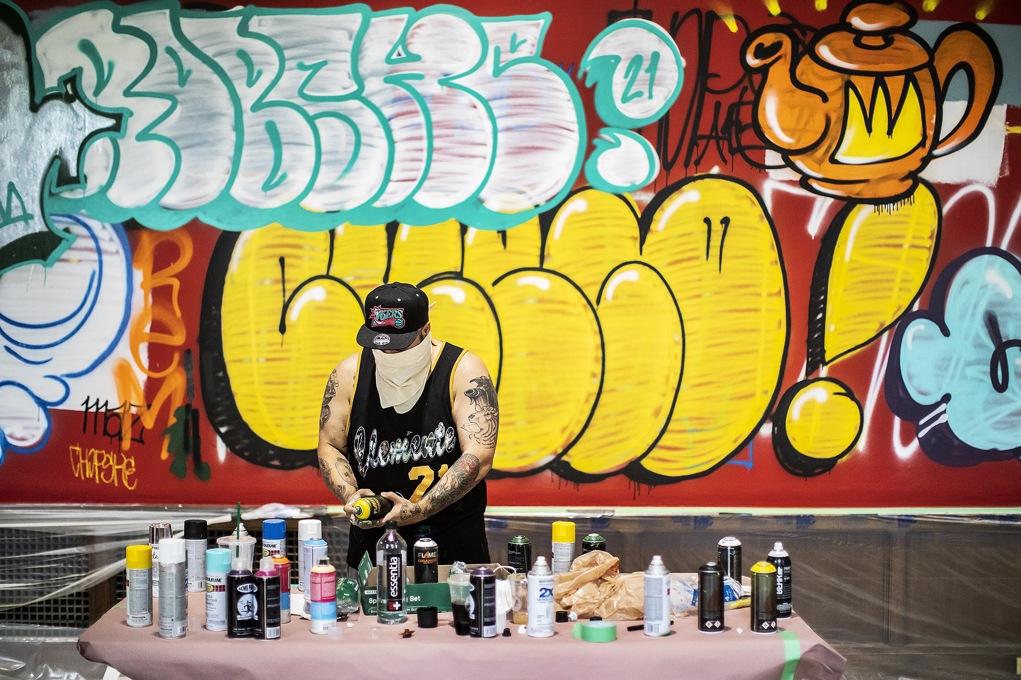 Artist standing at table with spray paint cans 