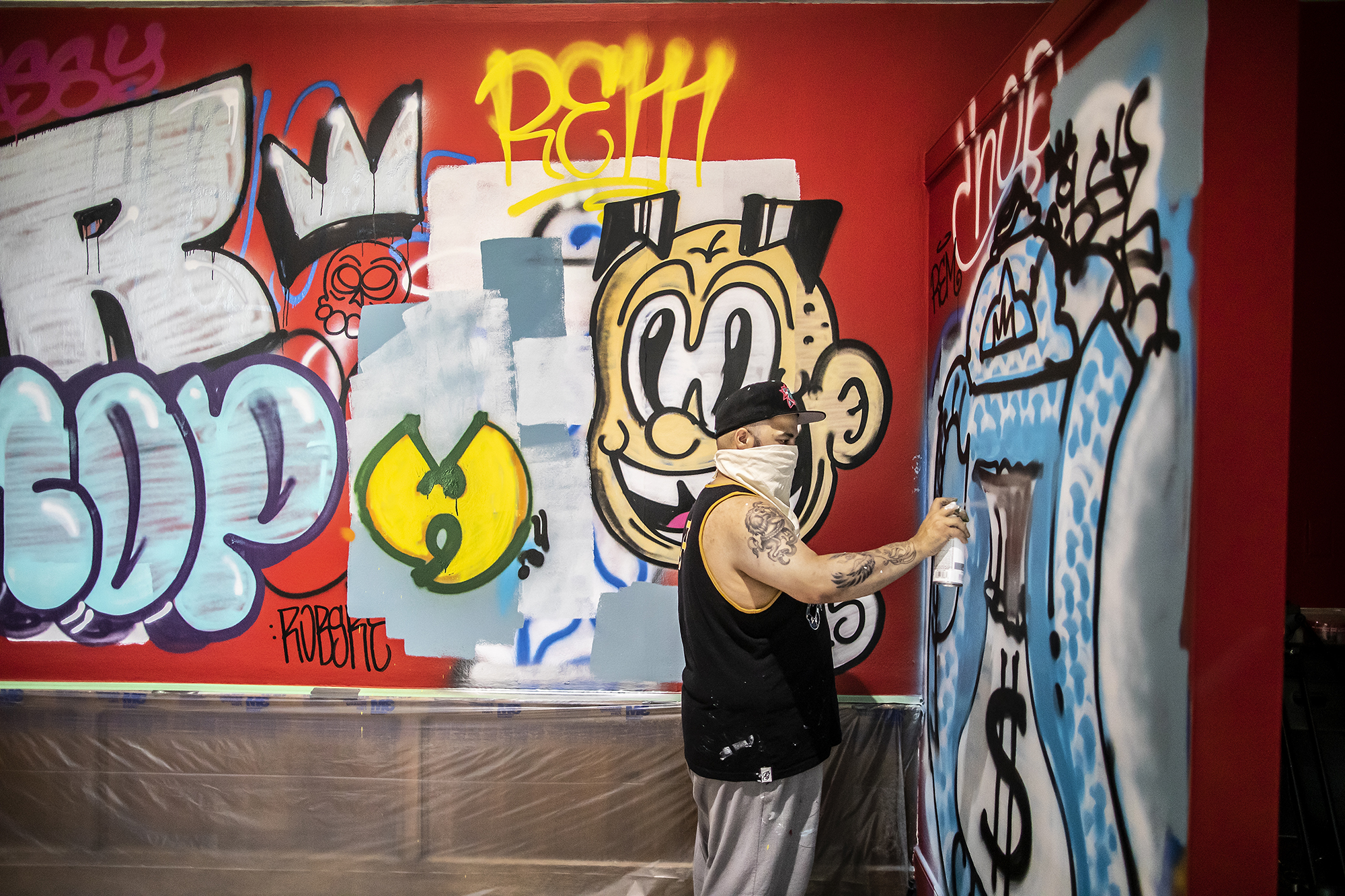 Artist spray-painting graffiti on wall of art gallery