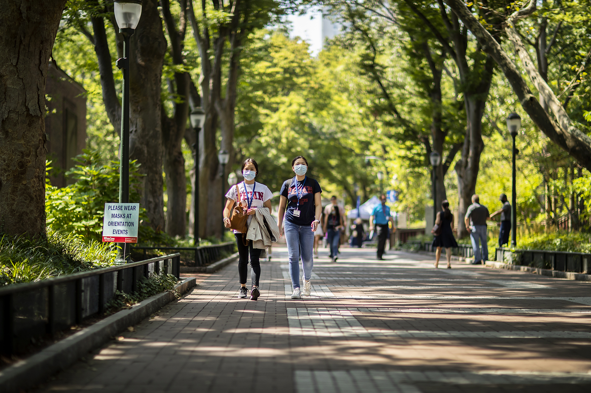 two people walking down locust walk wearing masks