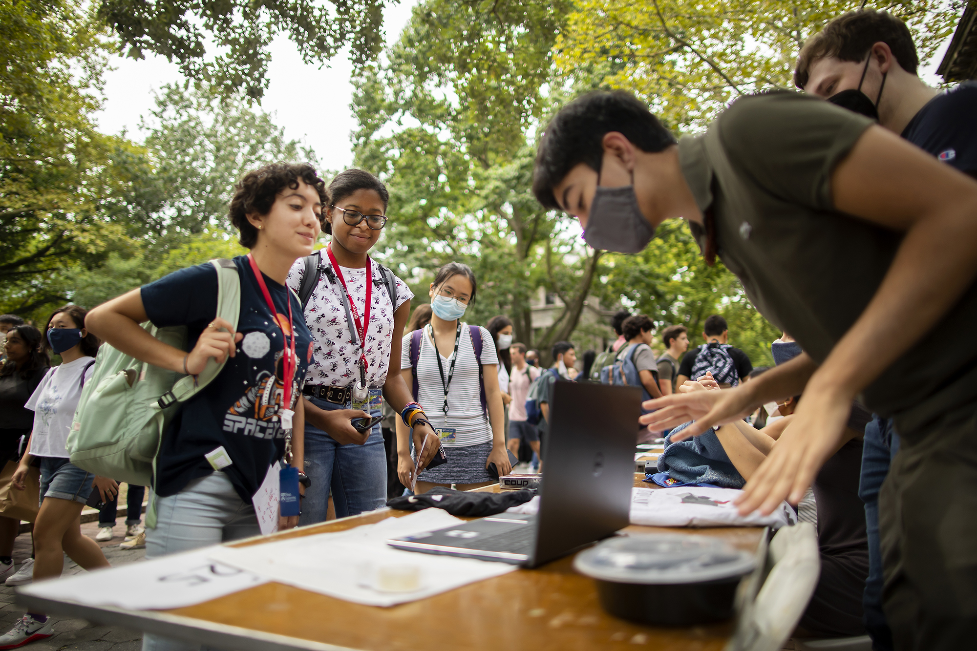 students standing at table outside looking at a laptop computer 