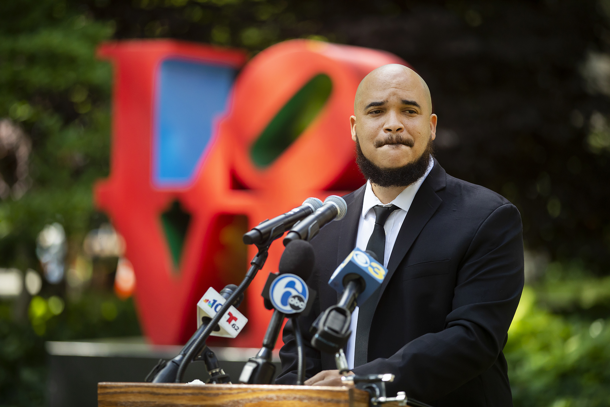Chaz Howard speaks at a podium in front of the LOVE statue on Penn’s campus.