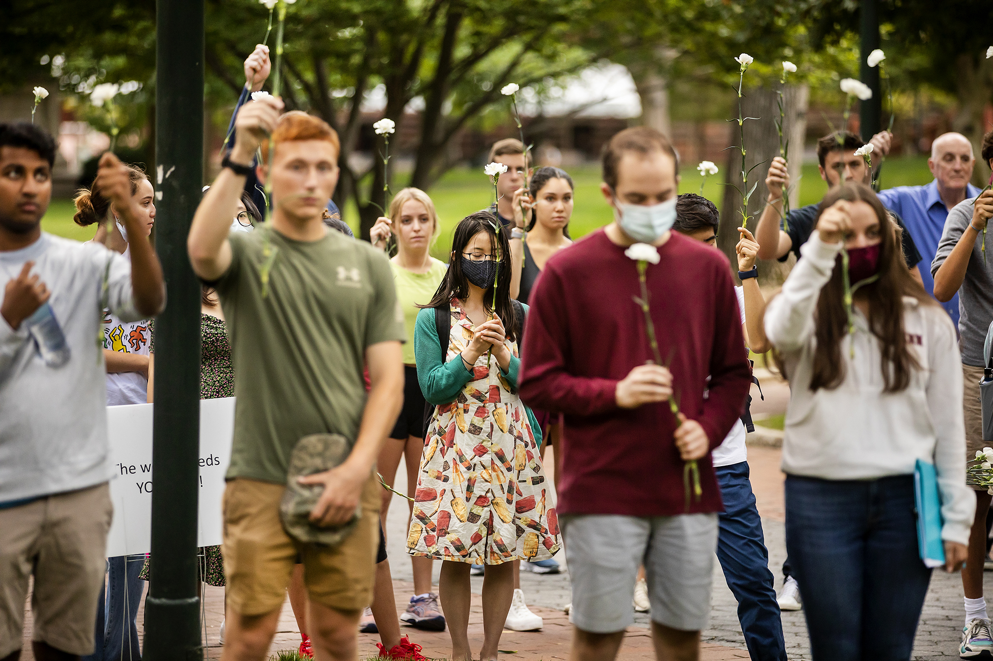 students hold white flowers up during moment of silence