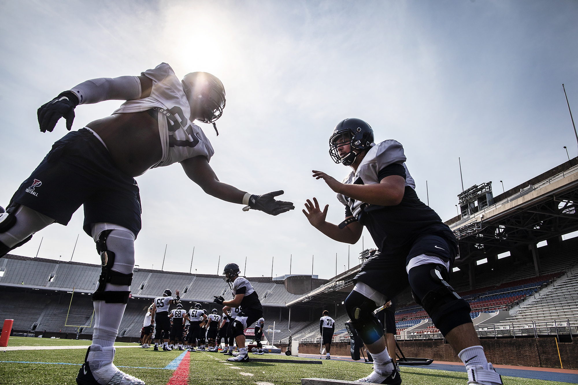 One player sticks his hand out to an offensive lineman during practice at Franklin Field.