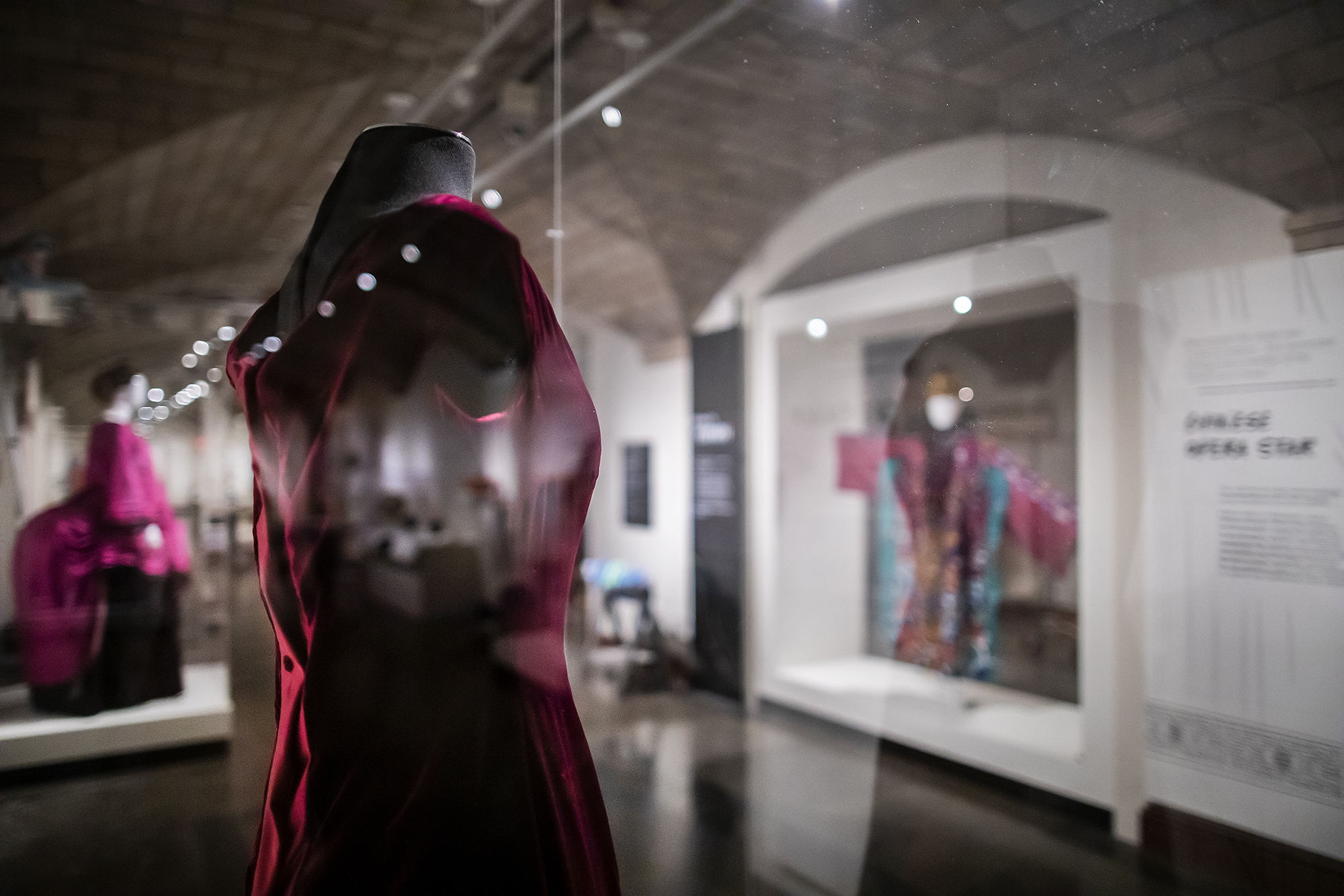 three garments in glass cases in a museum