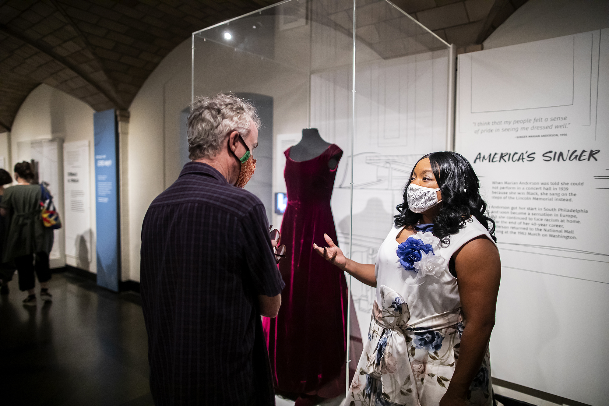 two people talking in front of a dress in a case