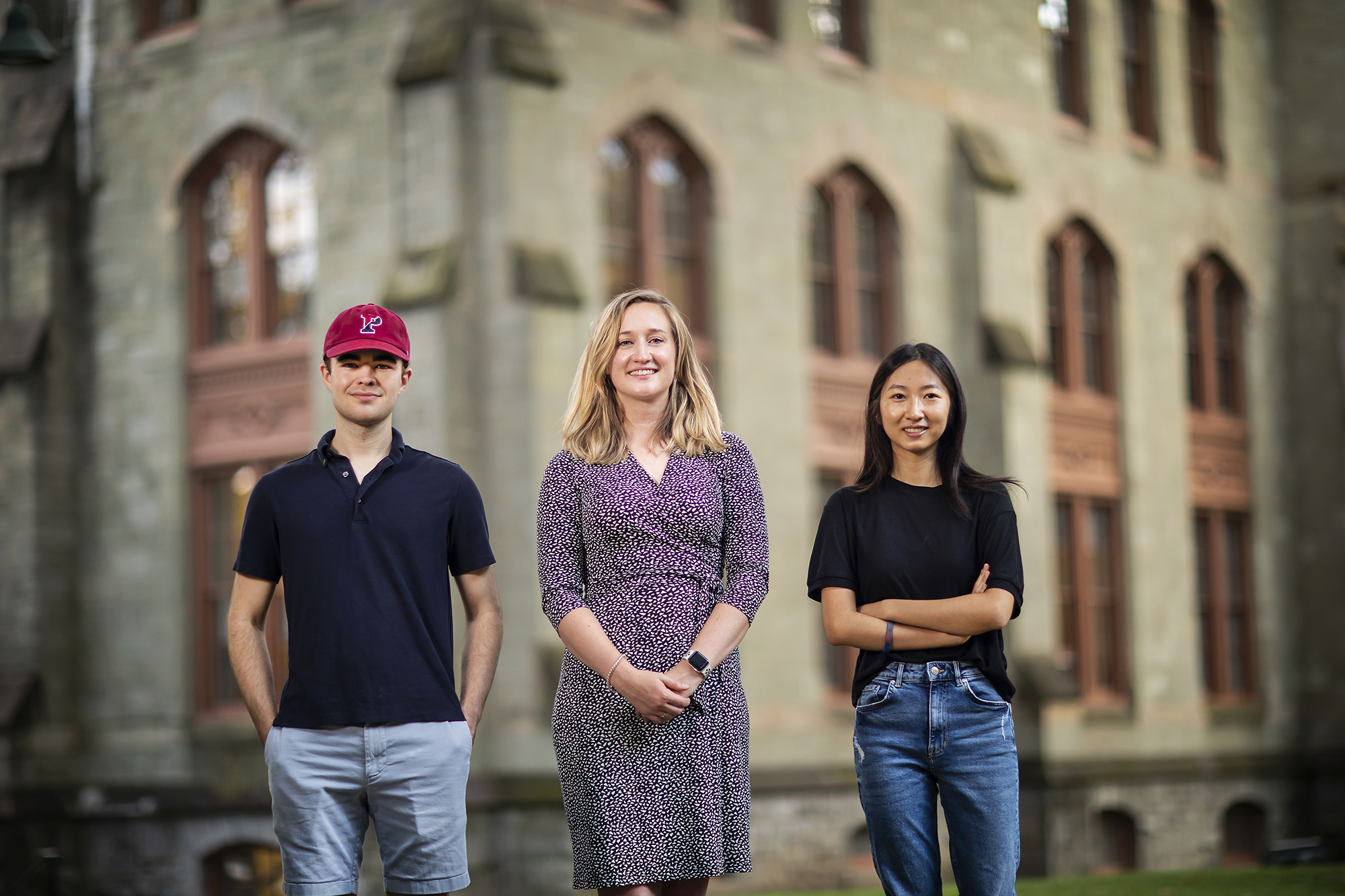 Three people stand in front of Cohen Hall