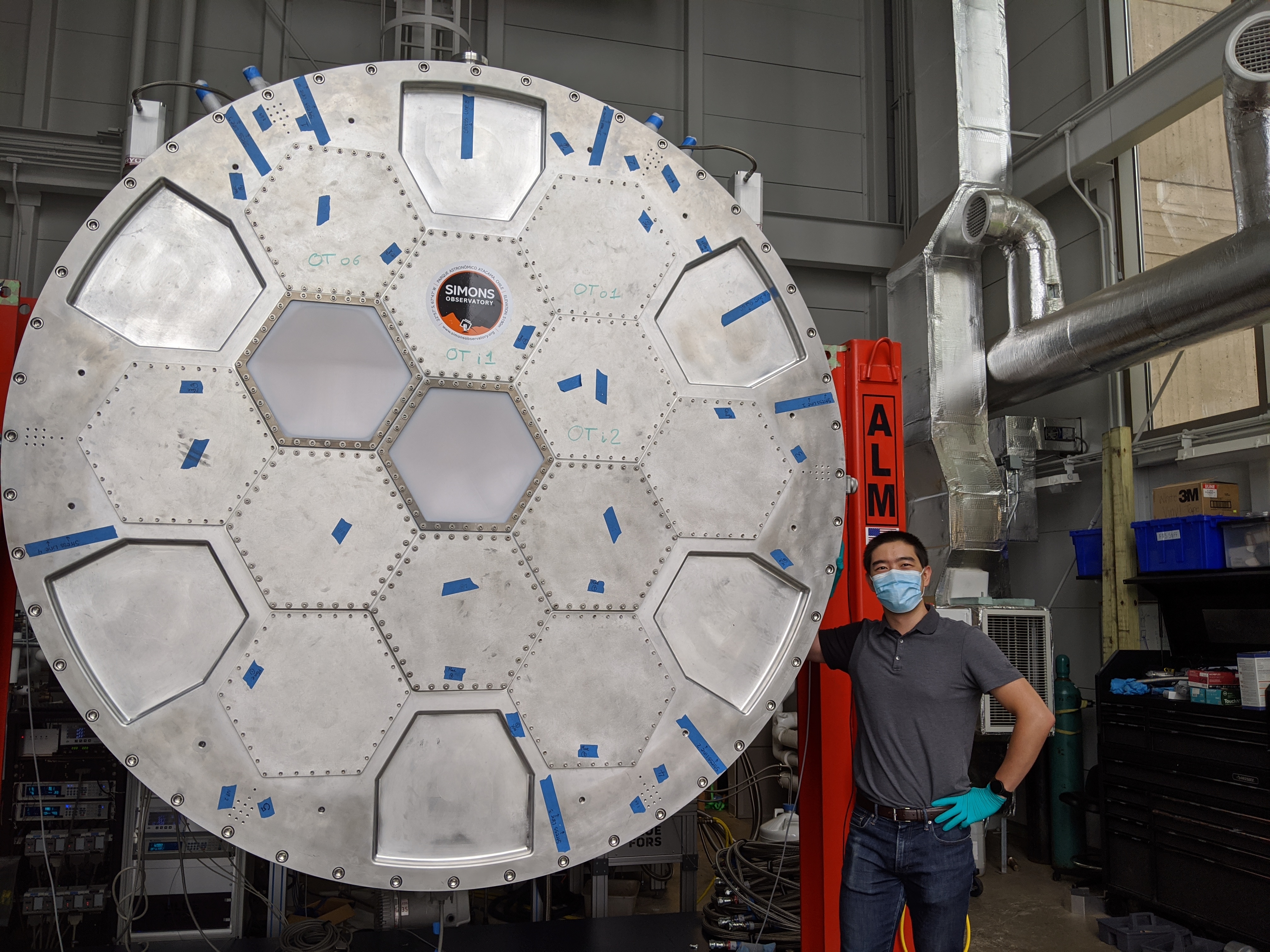 Ningfeng posing next to the large metal LATR inside of a research lab