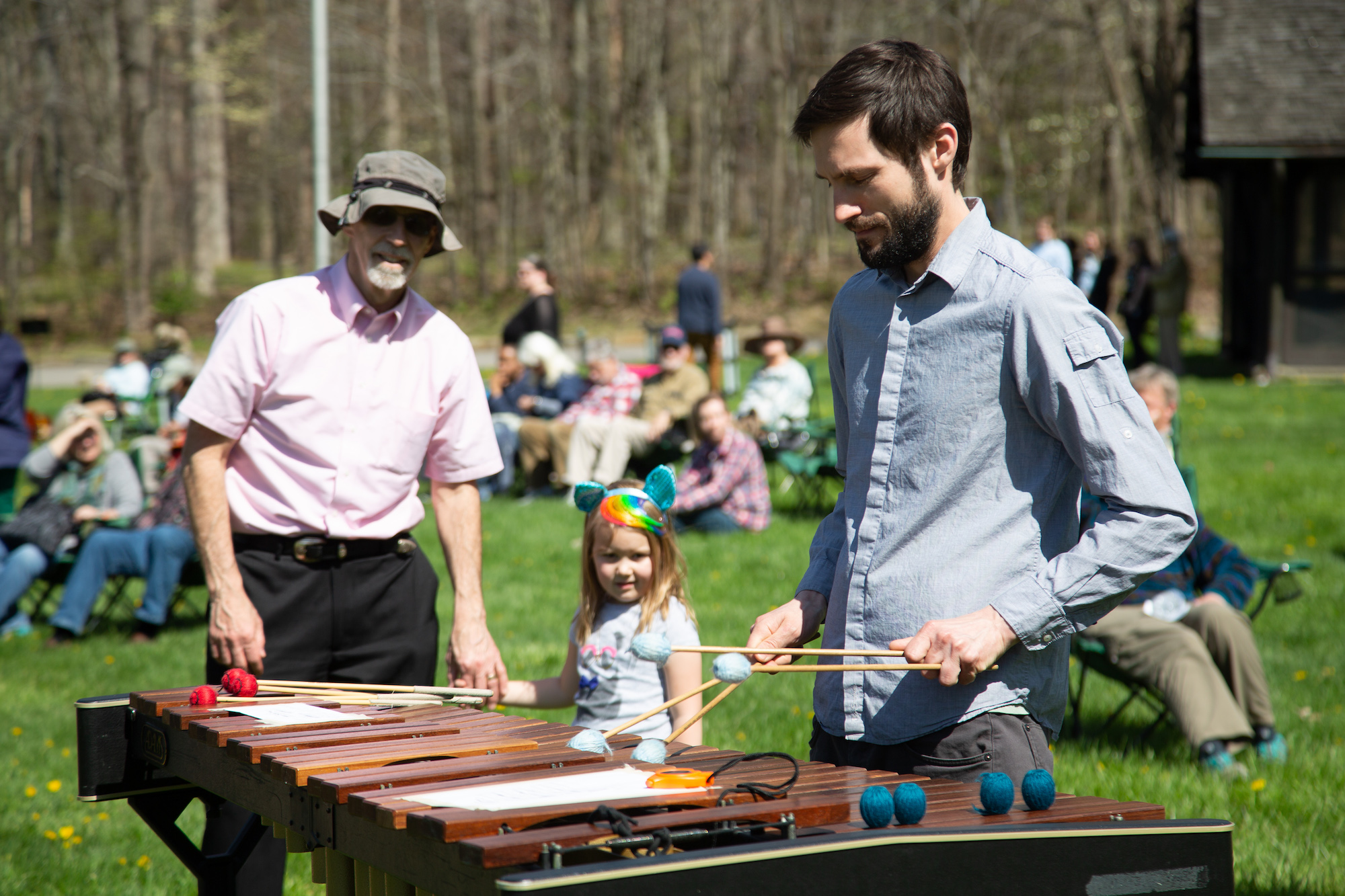 Man plays the xylophone while an older man and a child look on
