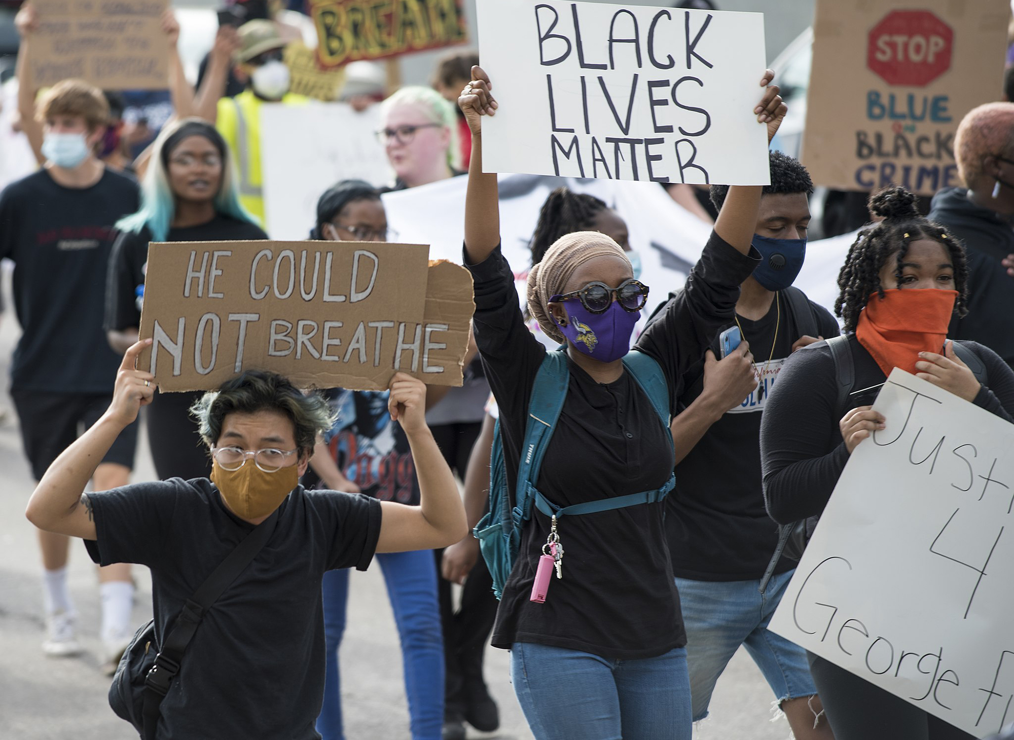 Masked people in a protest crowd holding signs that read Black Lives Matter, He Could Not Breathe, and Justice 4 George Floyd.