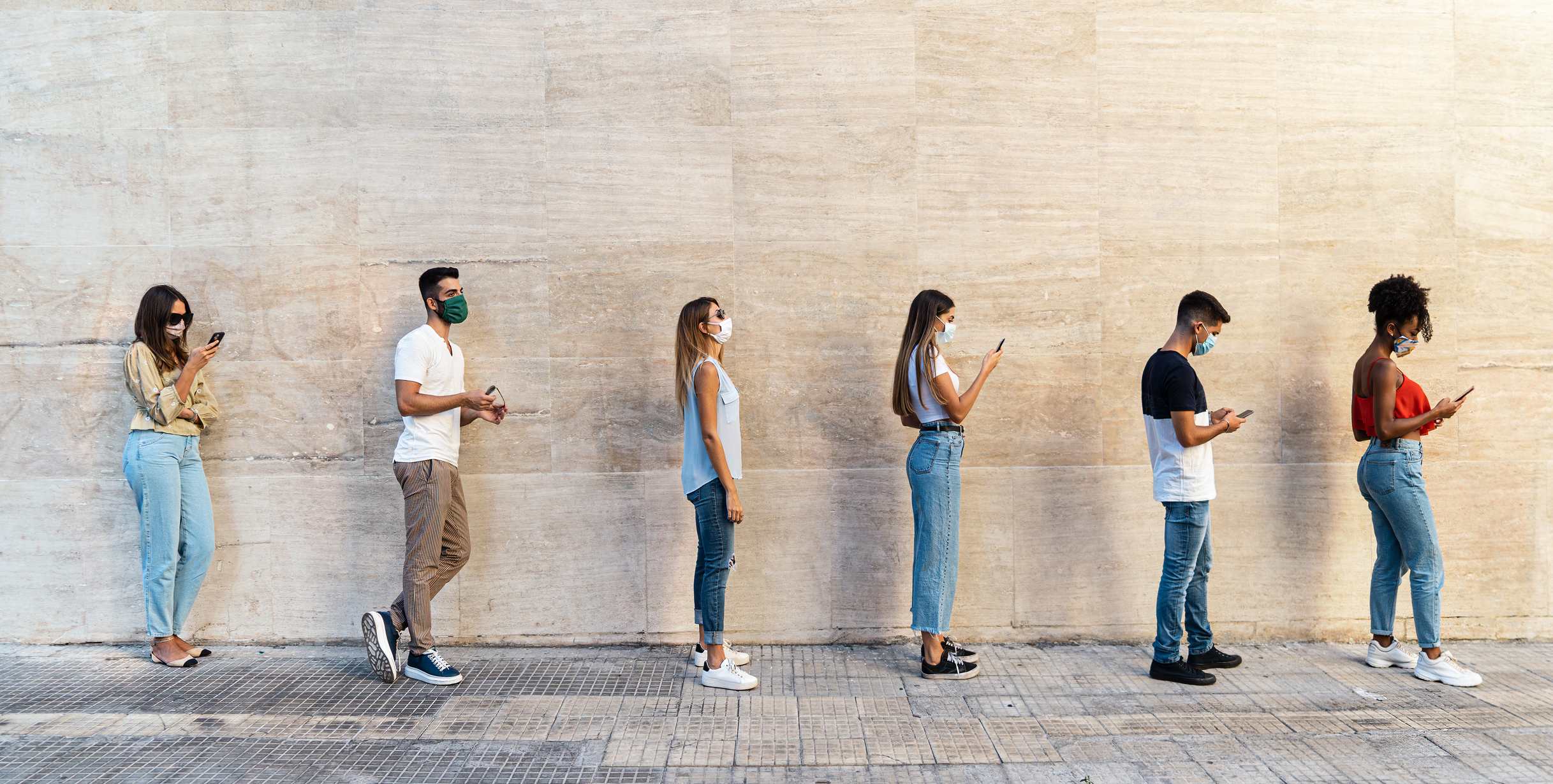 people standing outside in a line wearing masks