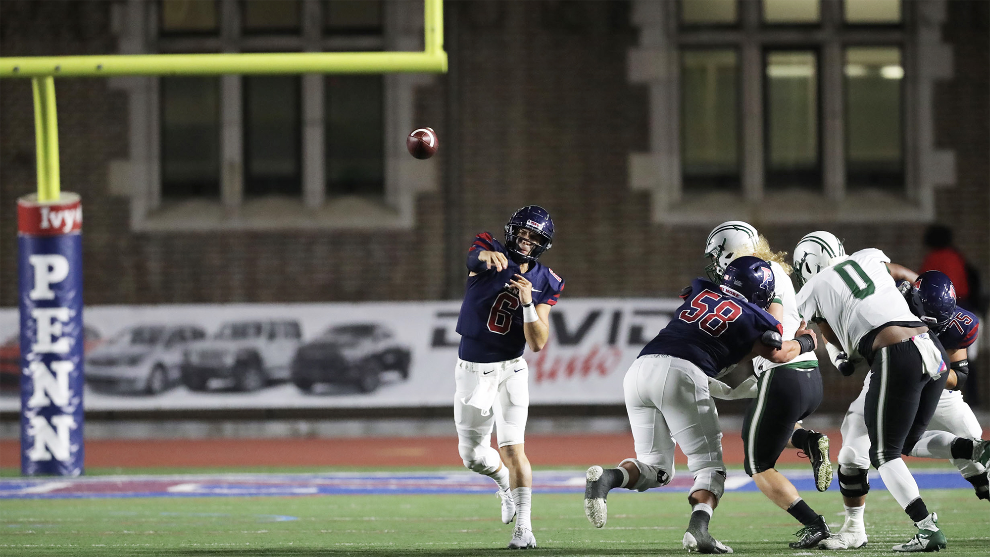 Quarterback John Quinnelly, in the middle of the frame, passes the ball down the field during a game.