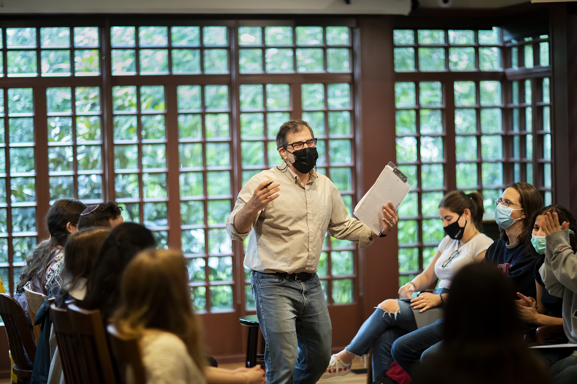 Al Filreis stands wearing a mask in a room full of students at the Kelly Writers House.