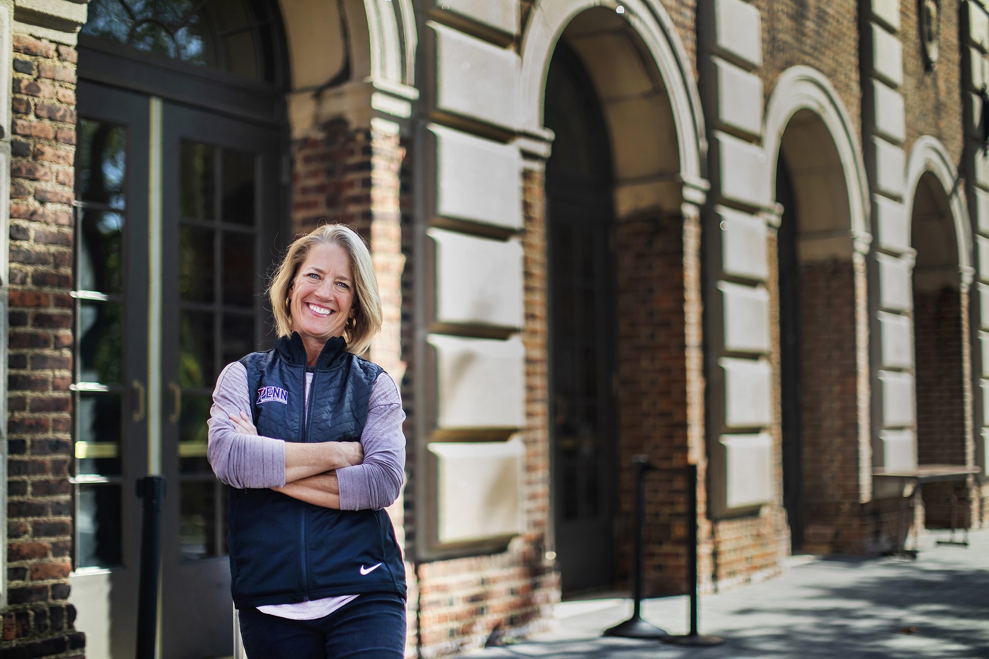 Andrea Wieland stands with her arms folded wearing a blue Penn vest outside of the Palestra.