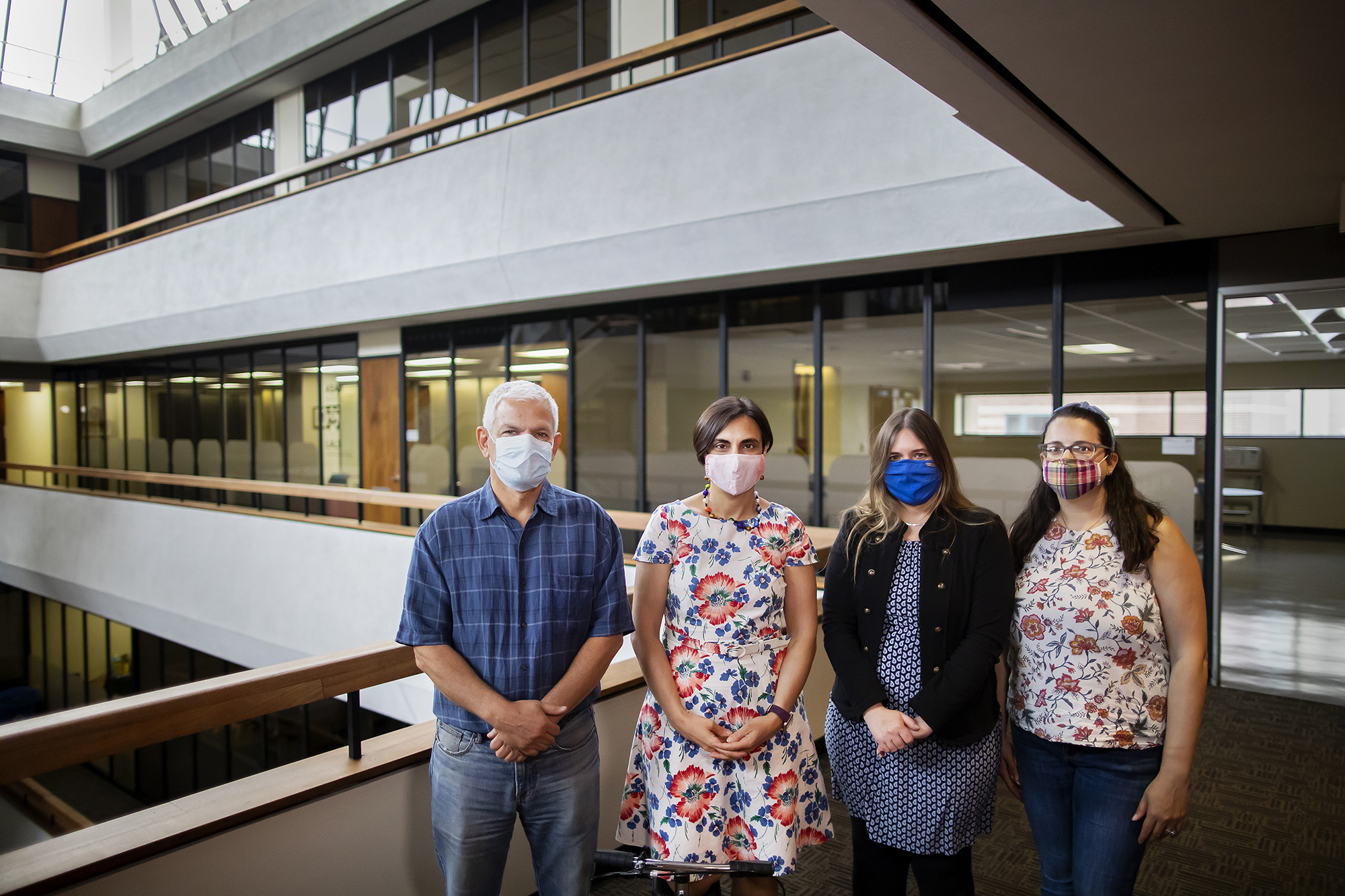 Four masked people stand together in the McNeil Building