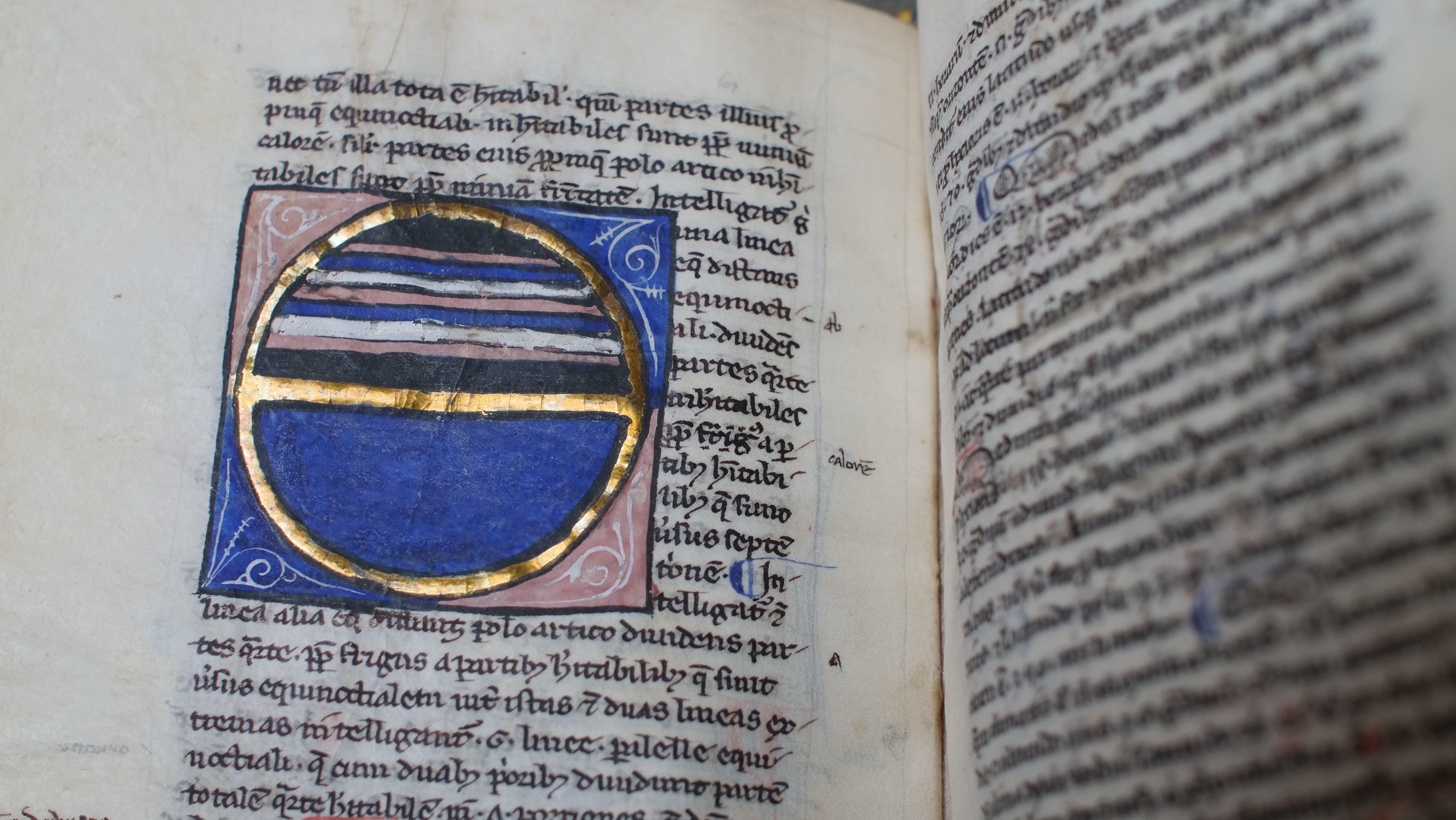 Open pages of John Trevisa book with ancient language and a round blue symbol among the text.