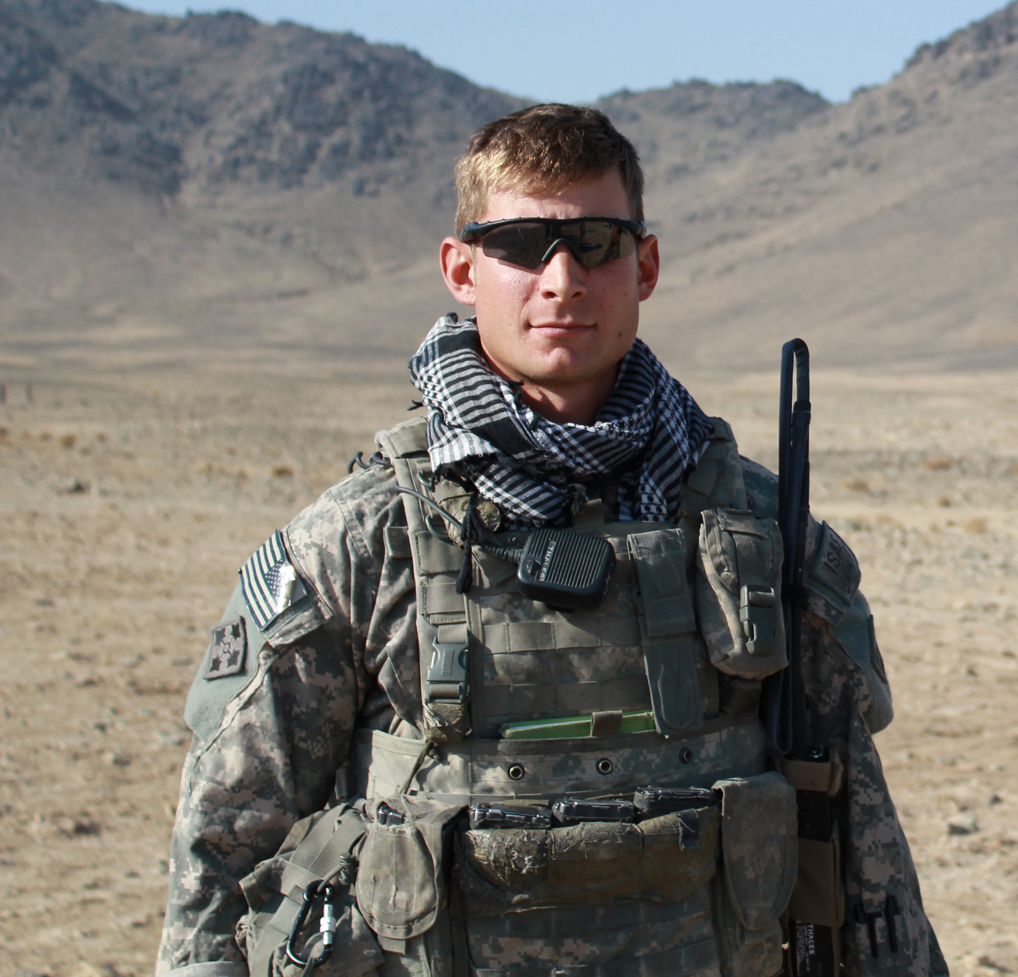 Jason Hartwig wearing military fatigues standing in a valley while deployed on duty.