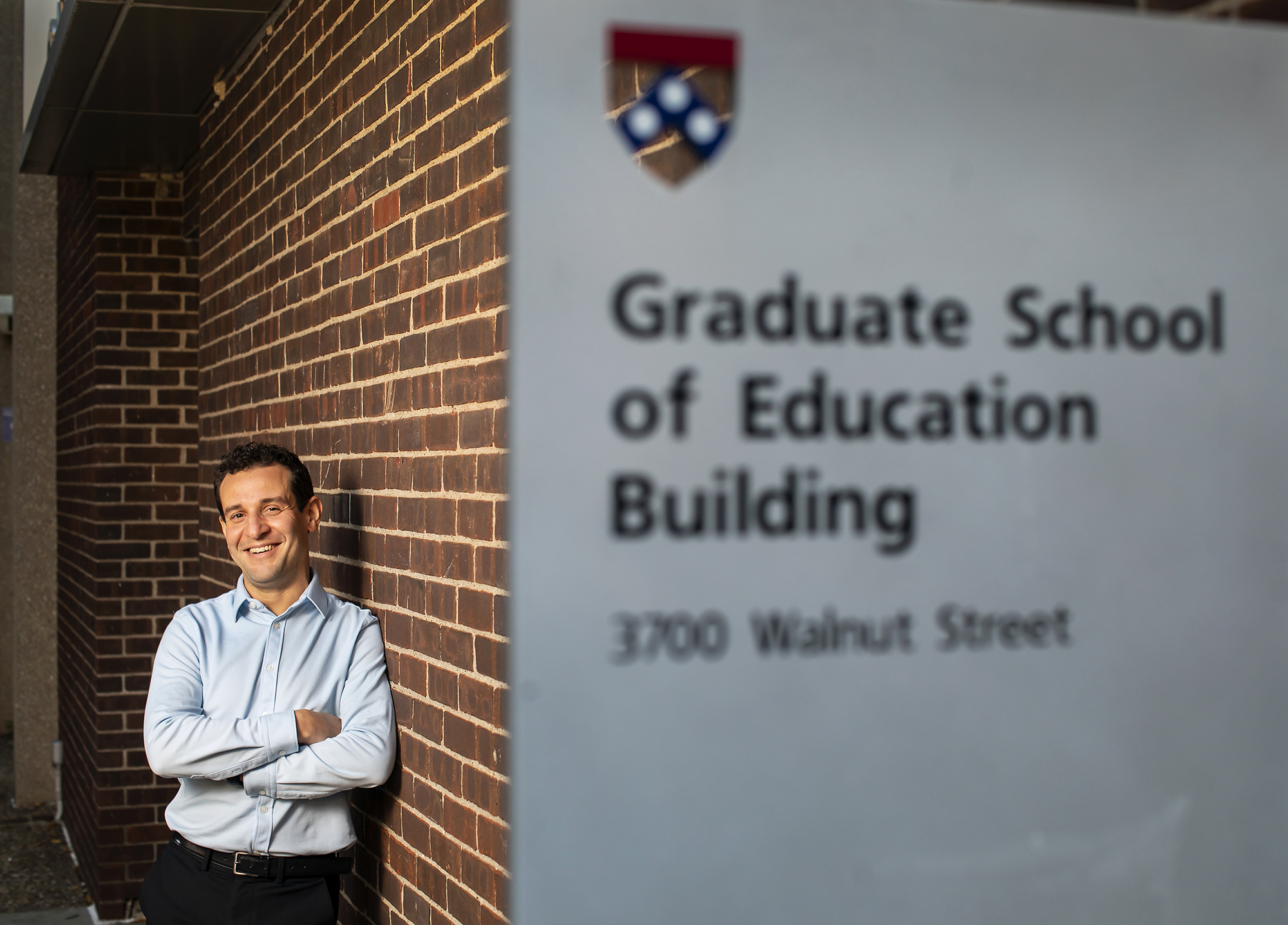 professor standing next to brick wall with Graduate School of Education Building sign