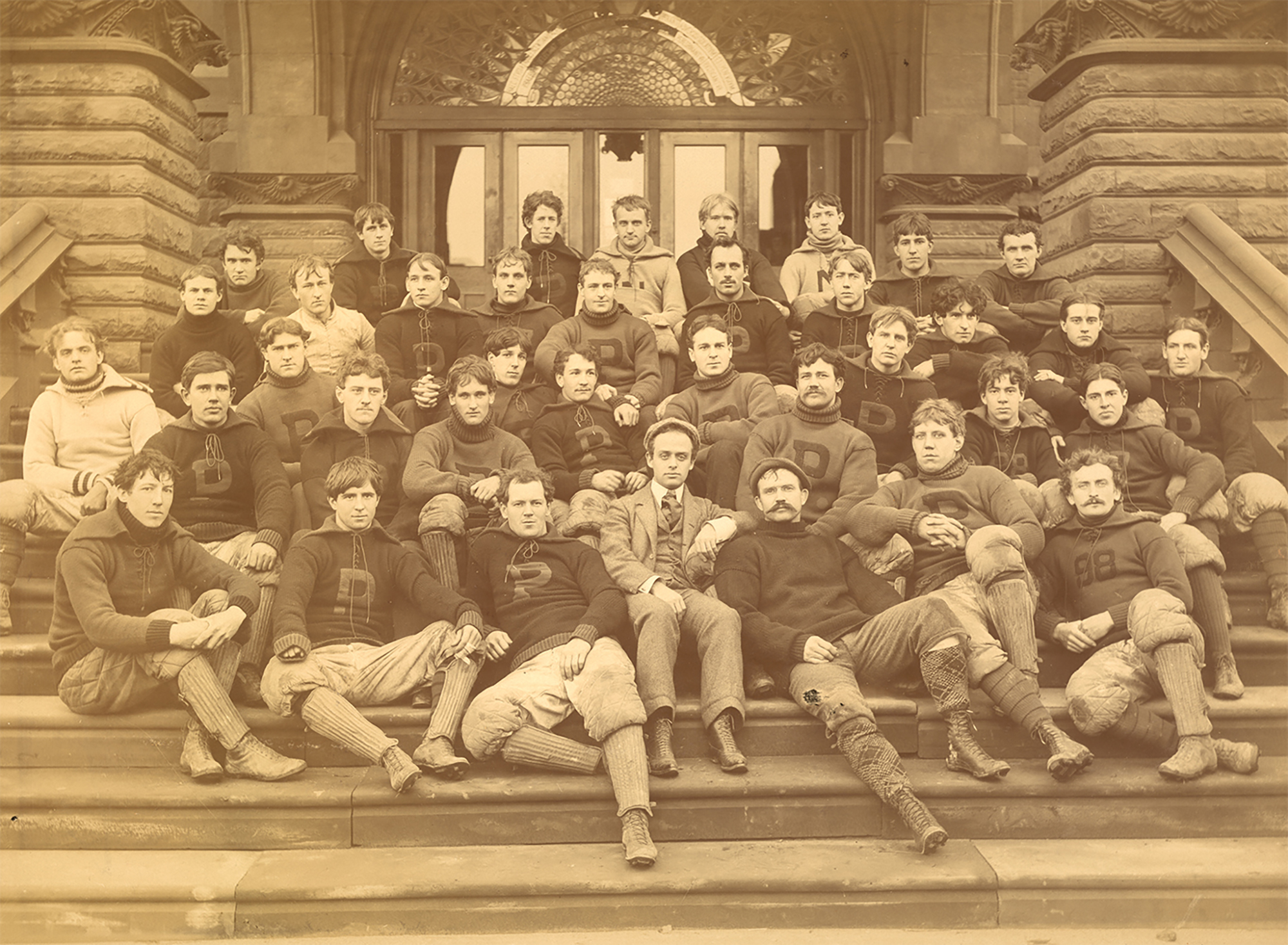 Members of Penn's 1895 football team pose together on steps.
