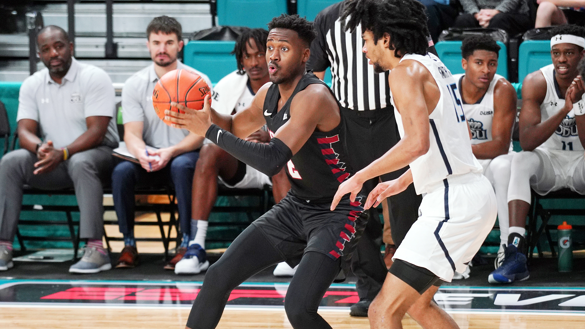 Wearing his black Penn jersey, guard Jonah Charles makes a move to the basket with the ball, while being guarded by a defender.