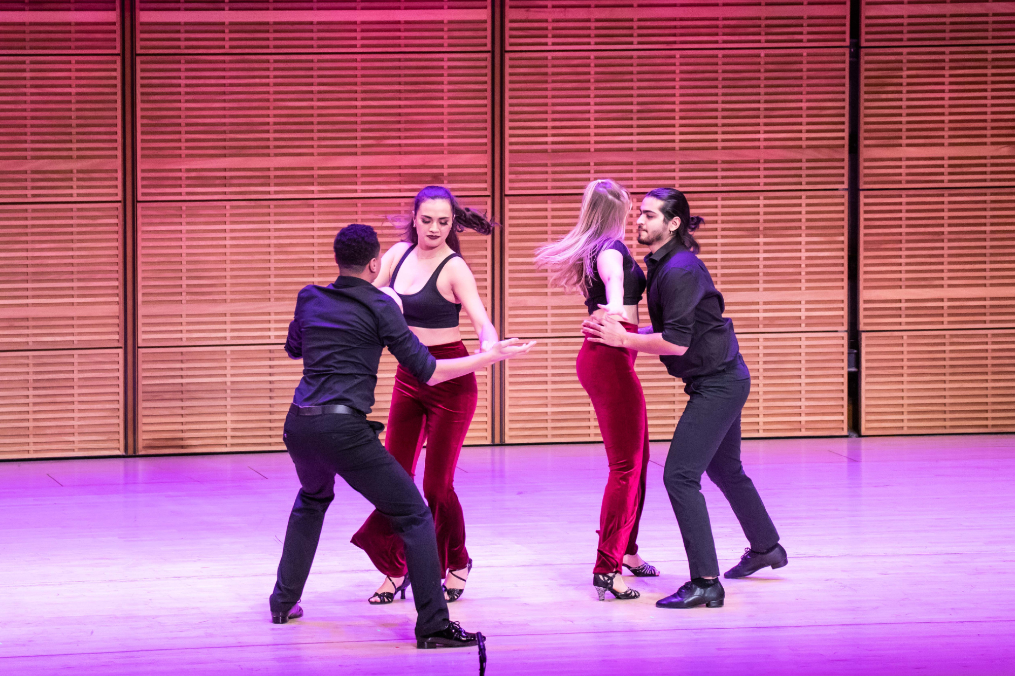 four students dancing on a stage 