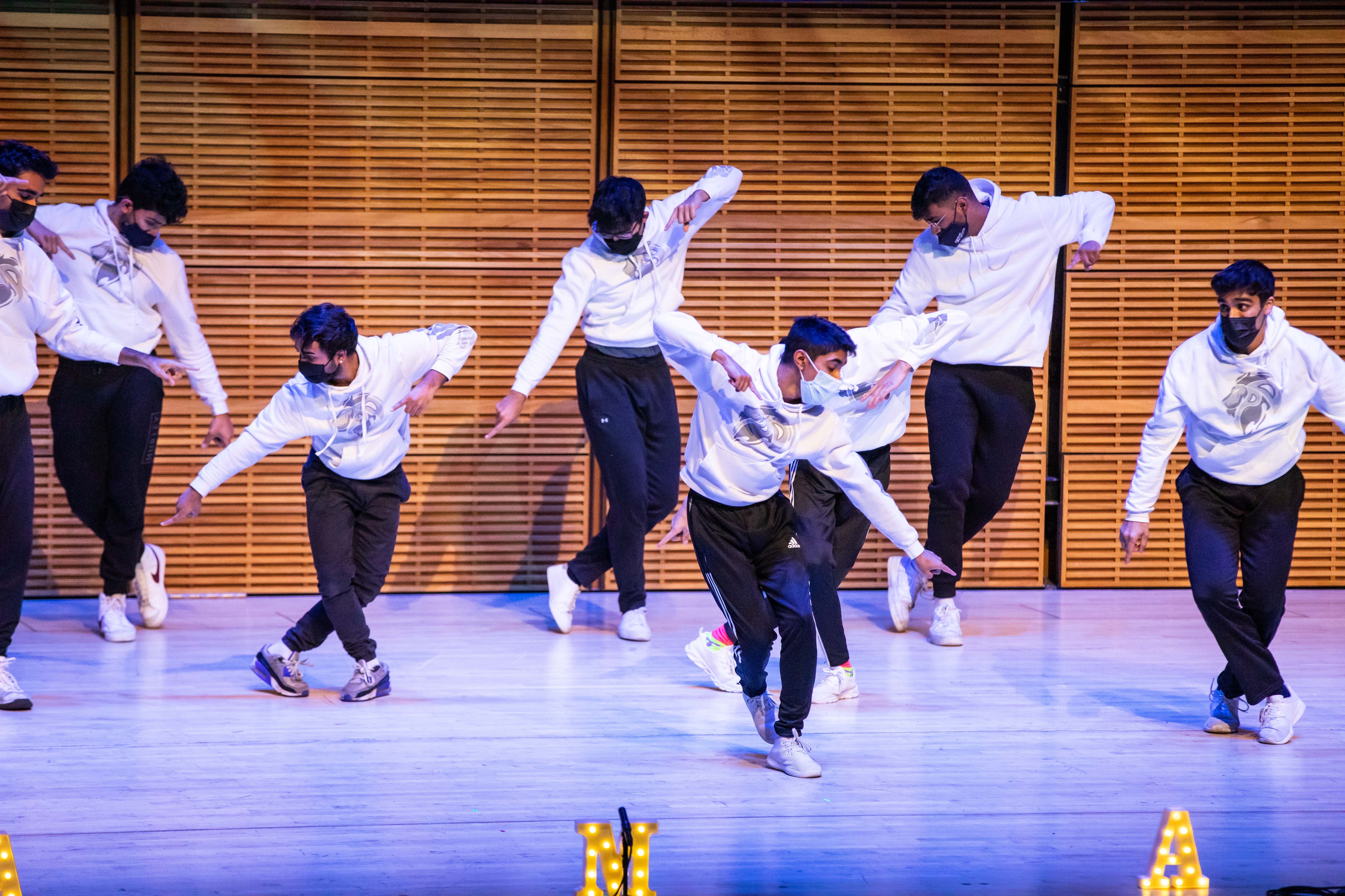 seven students dancing on a stage