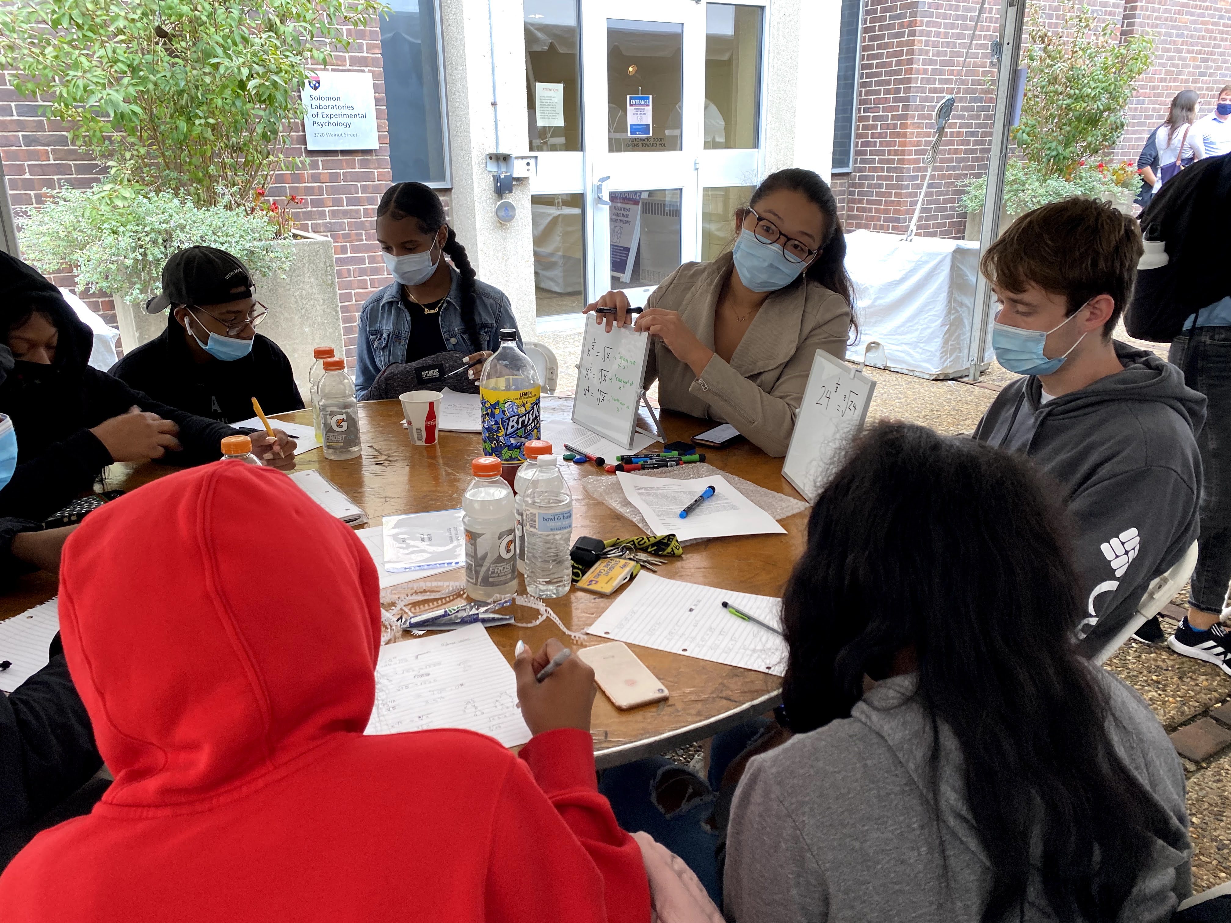 a group of students working at an outdoor tent on math equations