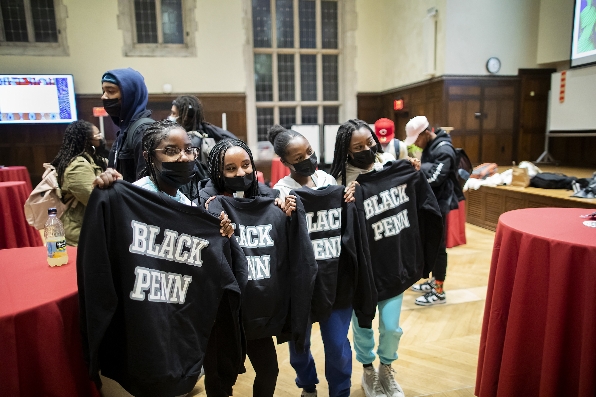 Four masked students smile holding sweatshirts reading, "Black Penn."