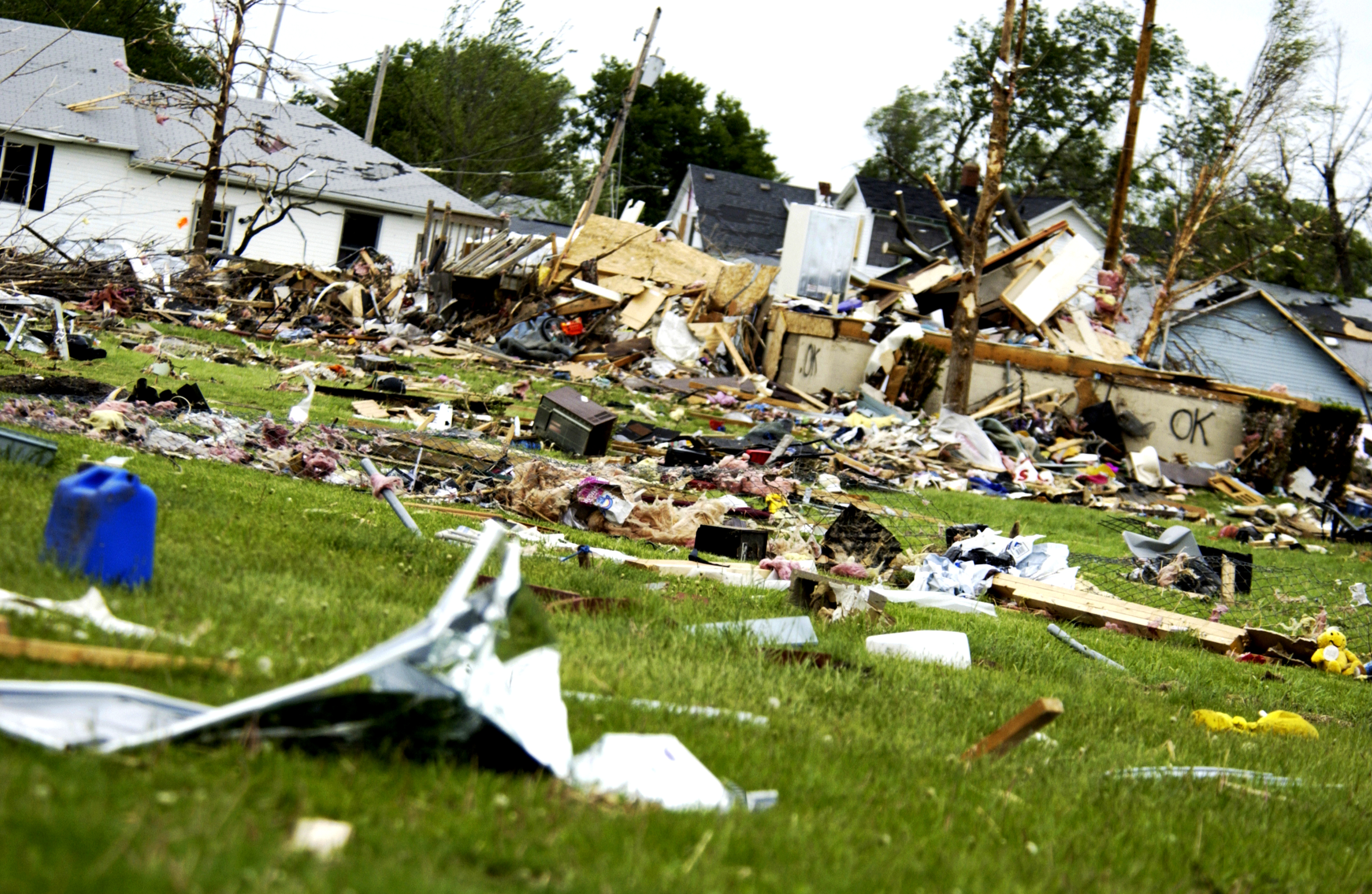 Aftermath of severe storm on a neighborhood with damaged houses and strewn debris.