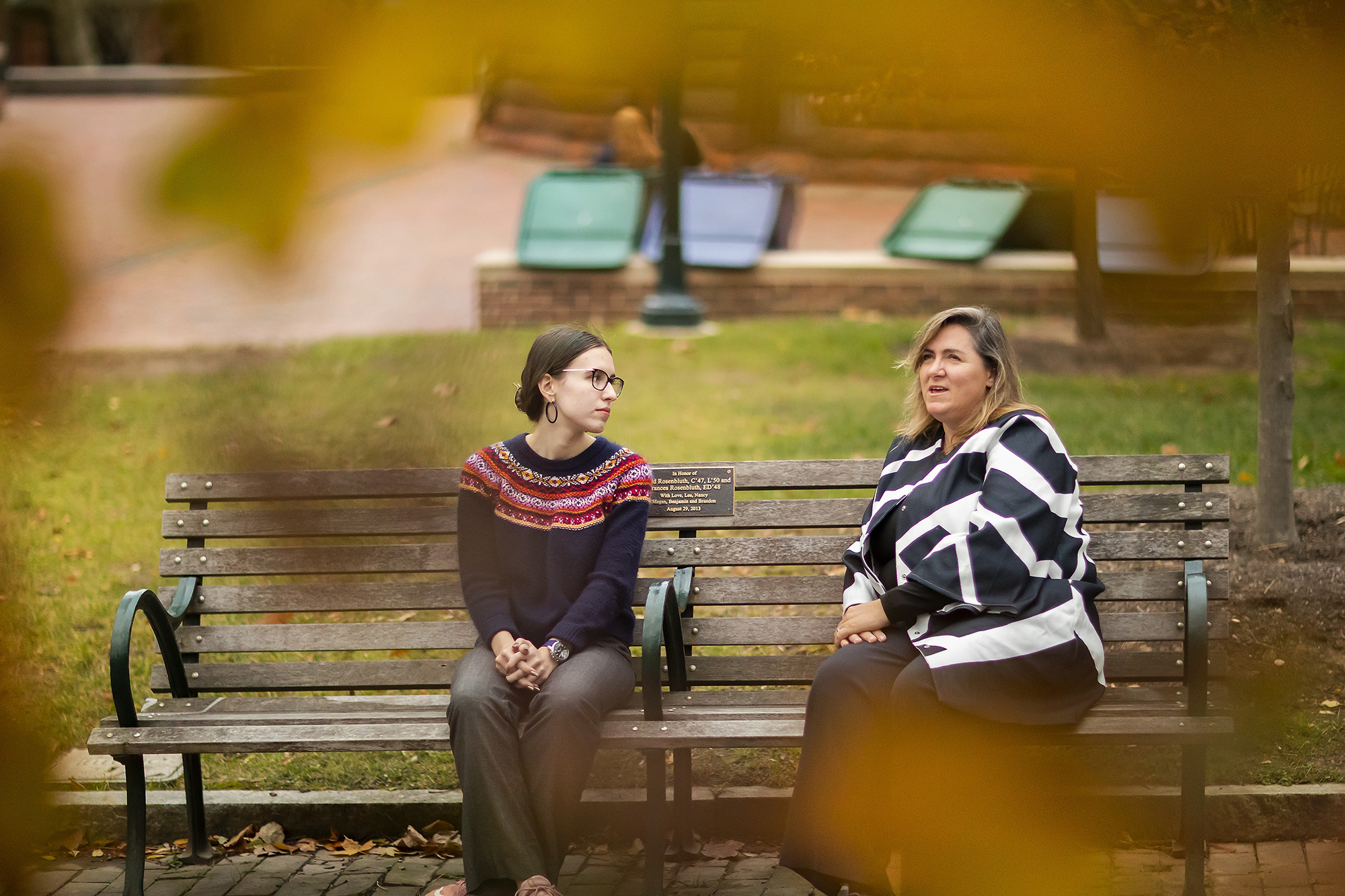 two people sitting on a bench and talking