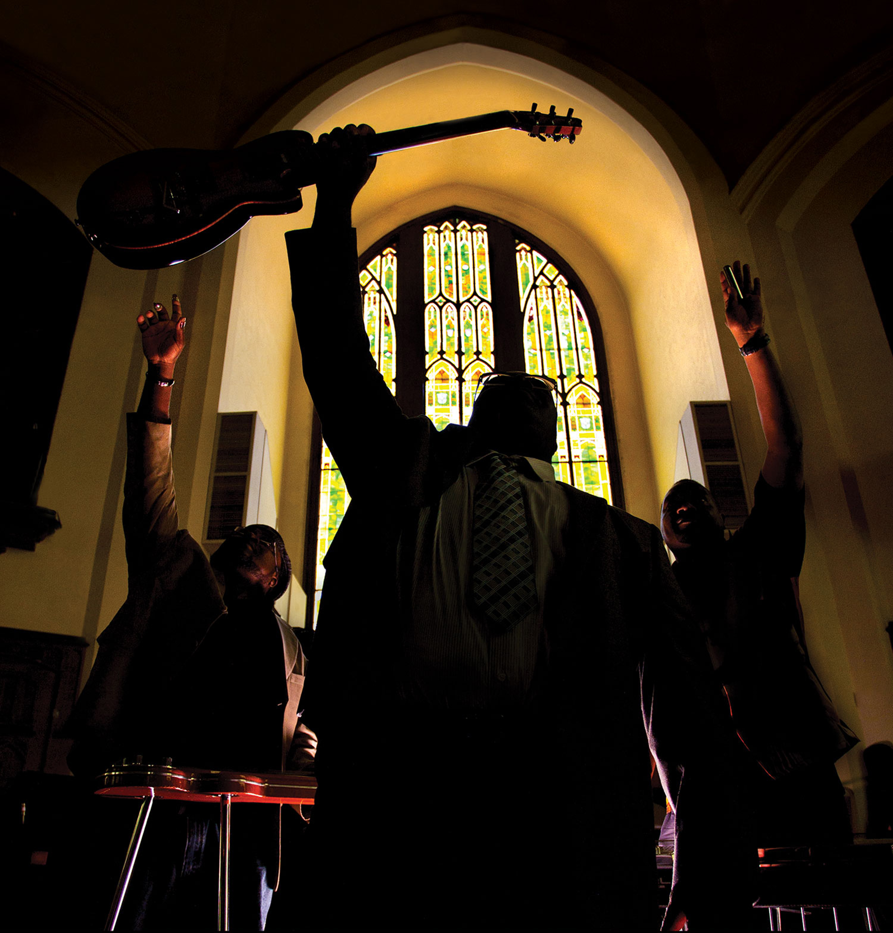 The Campbell Brothers raise their hands to the ceiling in a church