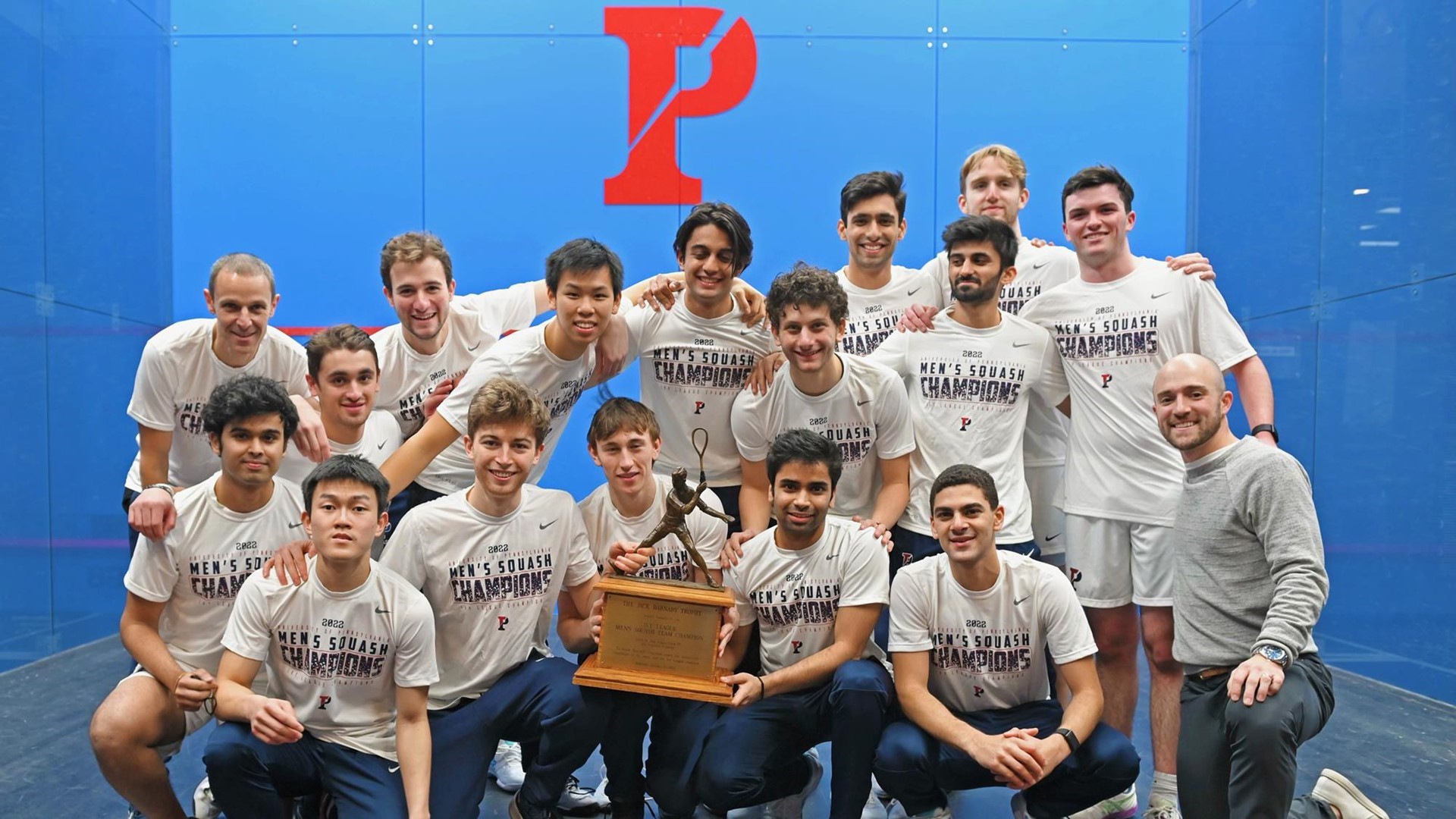 Members of the squash team pose at the Penn Squash Center with their championship trophy.