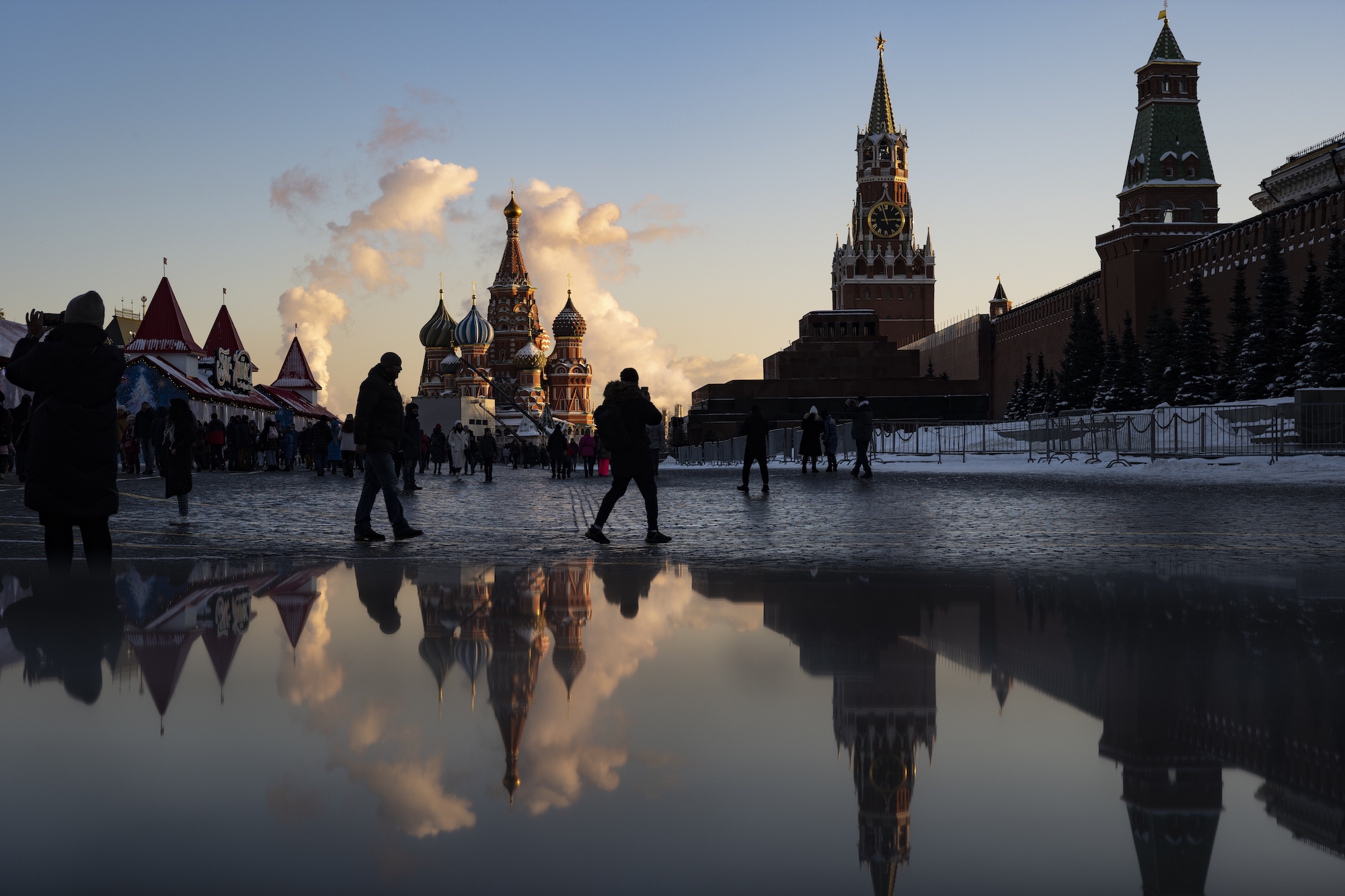 People walking in Moscow's Red Square are reflected in a puddle on the ground
